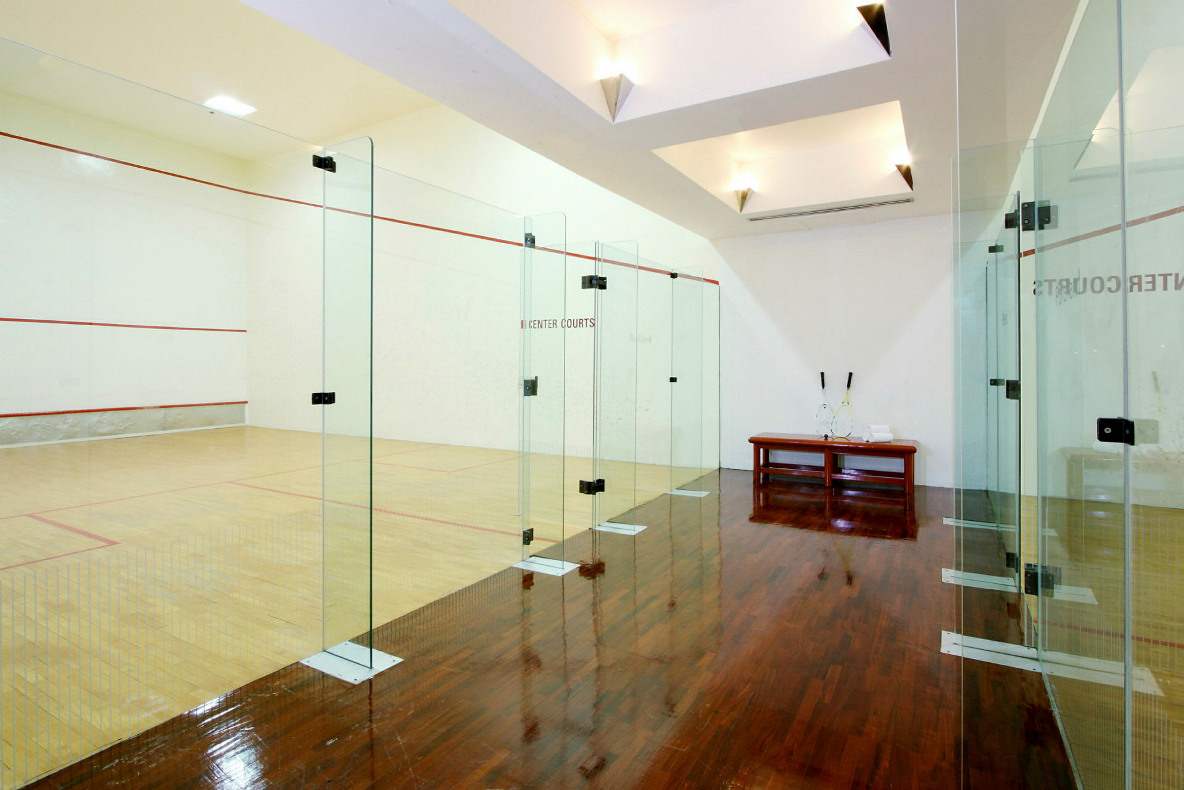 Squashhall med glassvegger og tregulv. (AI-generert tekst)