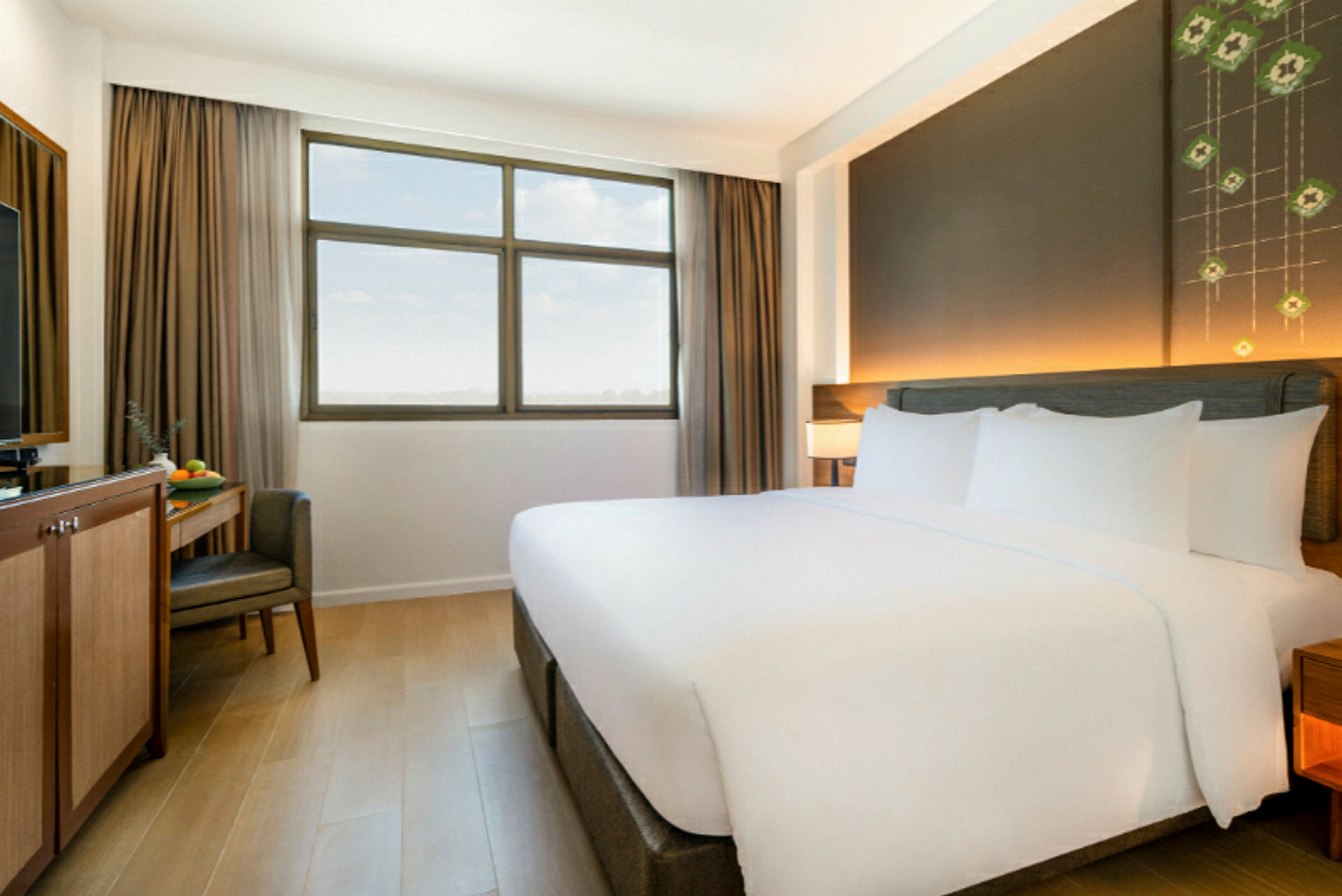 Et hotellrom med en stor dobbeltseng, et vindu med beige gardiner og et skrivebord med en stol og TV. (AI-generert tekst)
