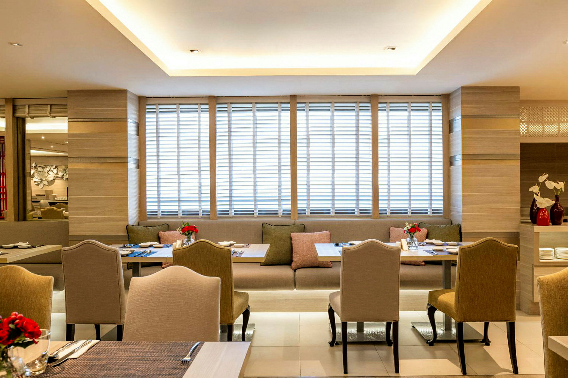 Bilde av en moderne restaurant med elegante stoler og bord samt sofaer, dekorert med friske blomster. (AI-generert tekst)