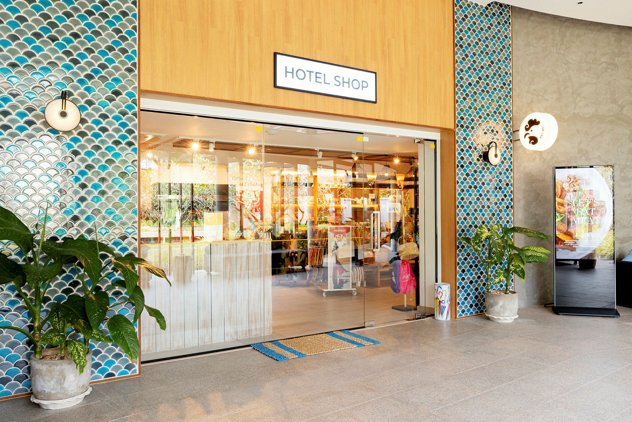 Inngangen til en hotellbutikk med glassdører og flislagte vegger. (AI-generert tekst)