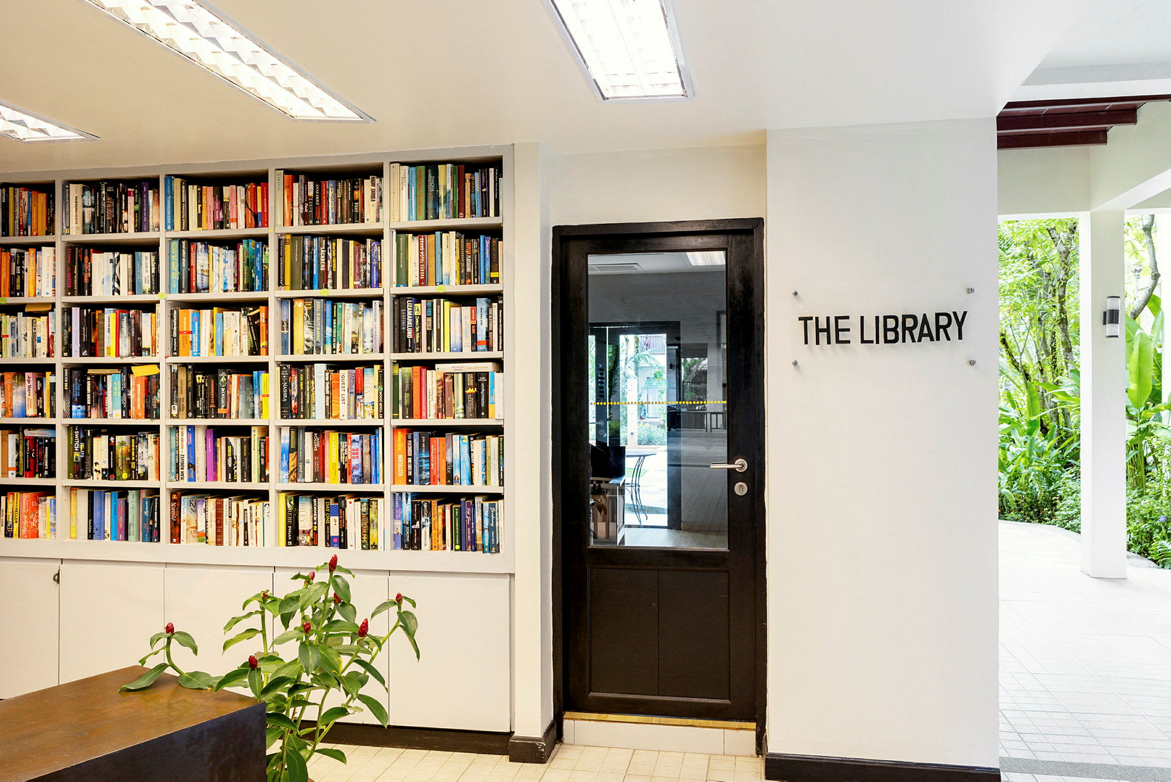 En bokhylle full av bøker ved siden av en dør med skiltet "The Library". (AI-generert tekst)