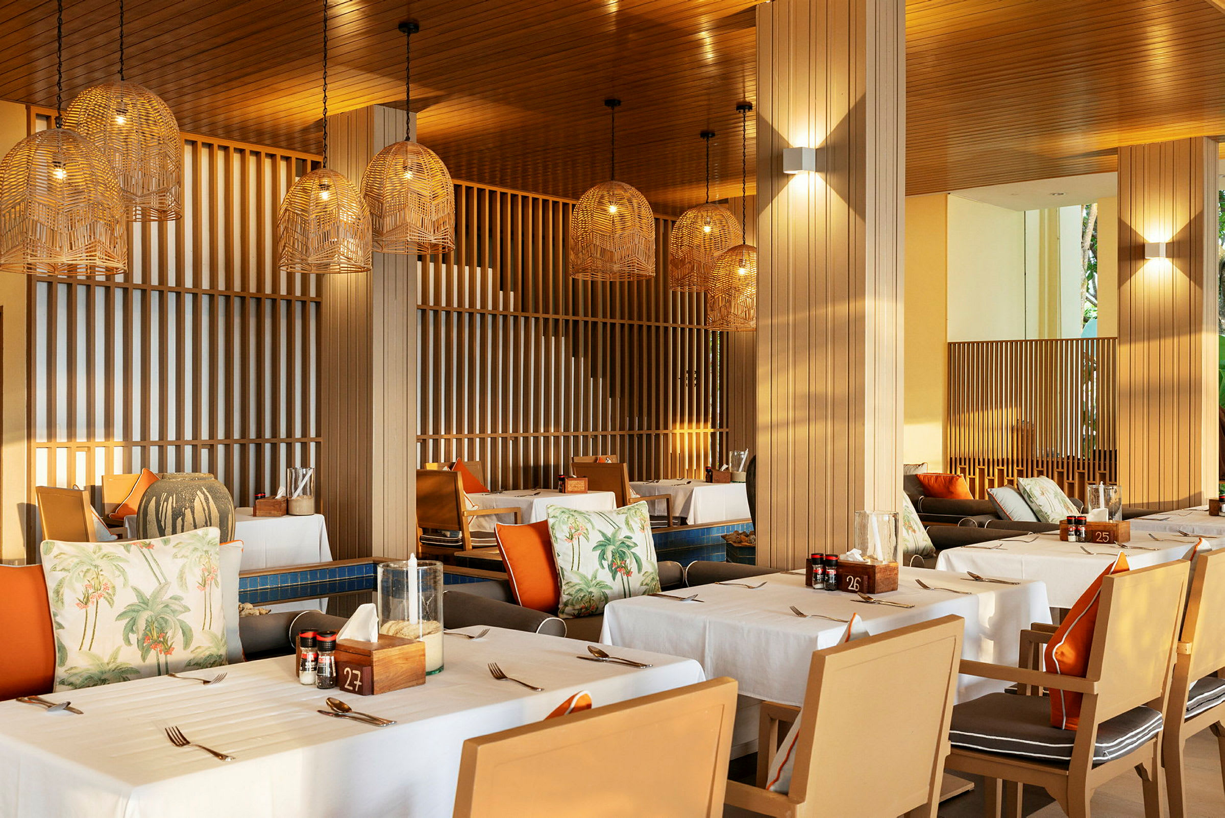 En restaurant med dekkede bord og hengende lampeskjermer i flettet design. (AI-generert tekst)