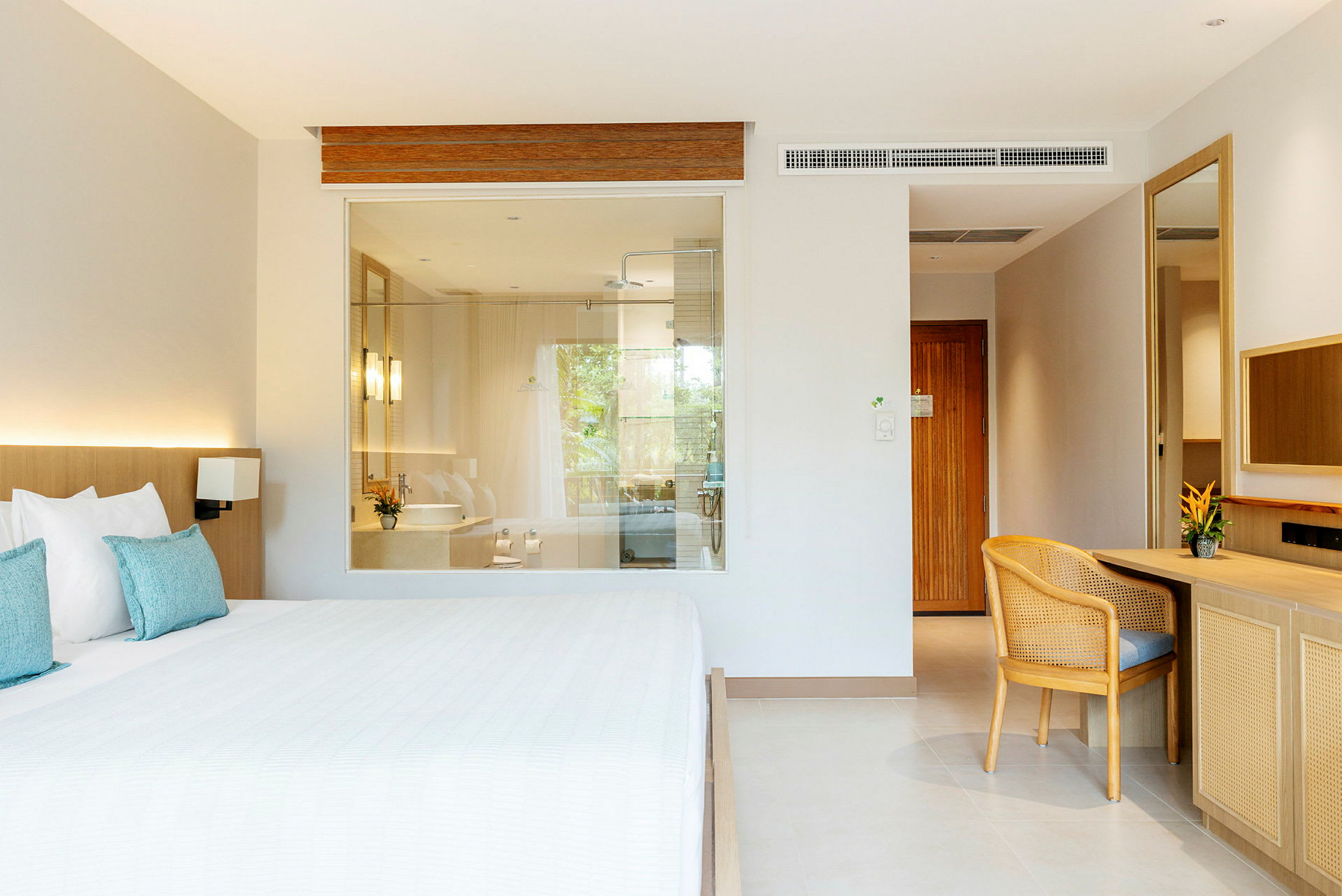 Hotellrom med seng, skrivebord og en glassvegg til badet. (AI-generert tekst)