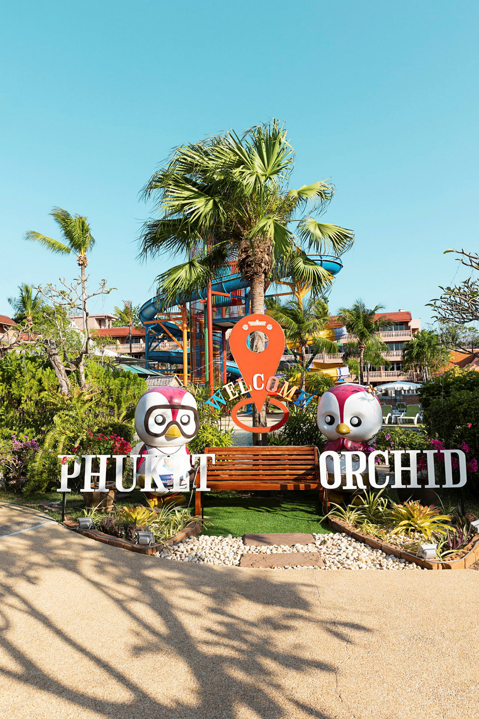Inngang til Phuket Orchid med palmer i bakgrunnen. (AI-generert tekst)