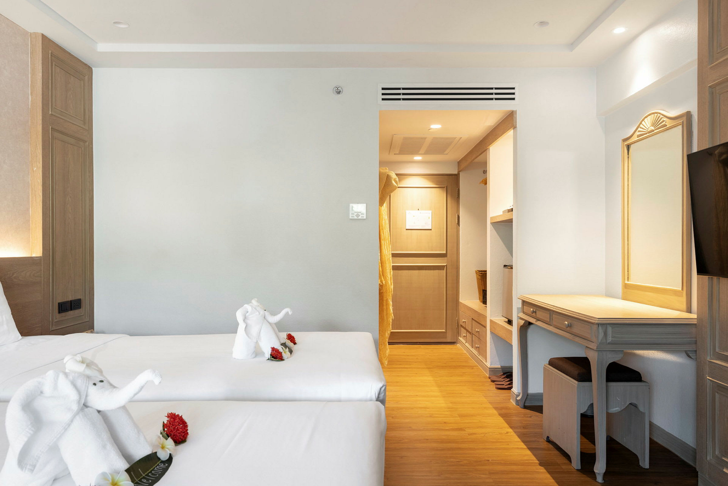 Hotellrom med to enkeltsenger, dekorert med håndkledfigurer. Innredning inkluderer skrivebord og inngang til garderobe. (AI-generert tekst)