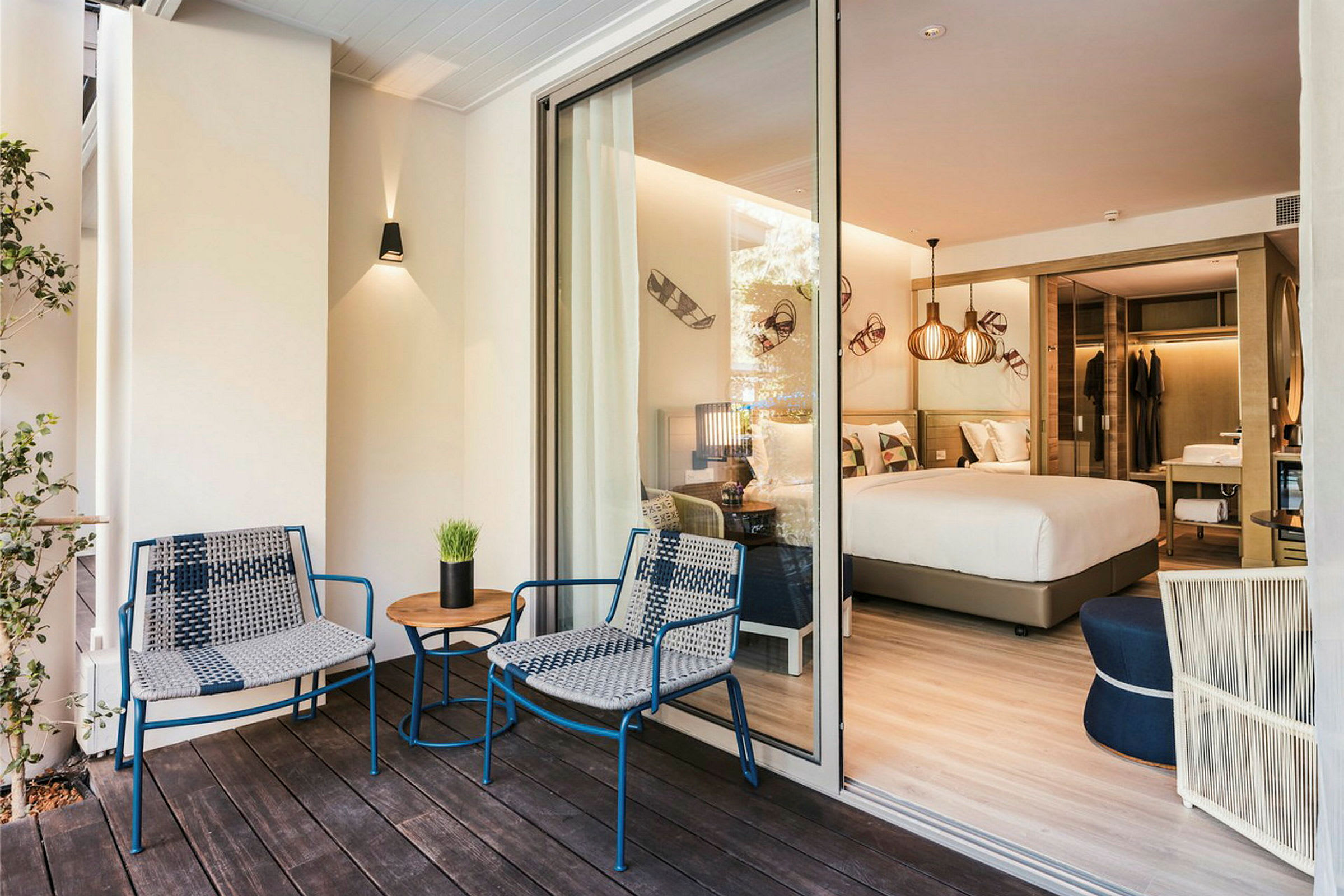 Et hotellrom med dobbeltseng og åpning mot en terrasse med sittemøbler. (AI-generert tekst)