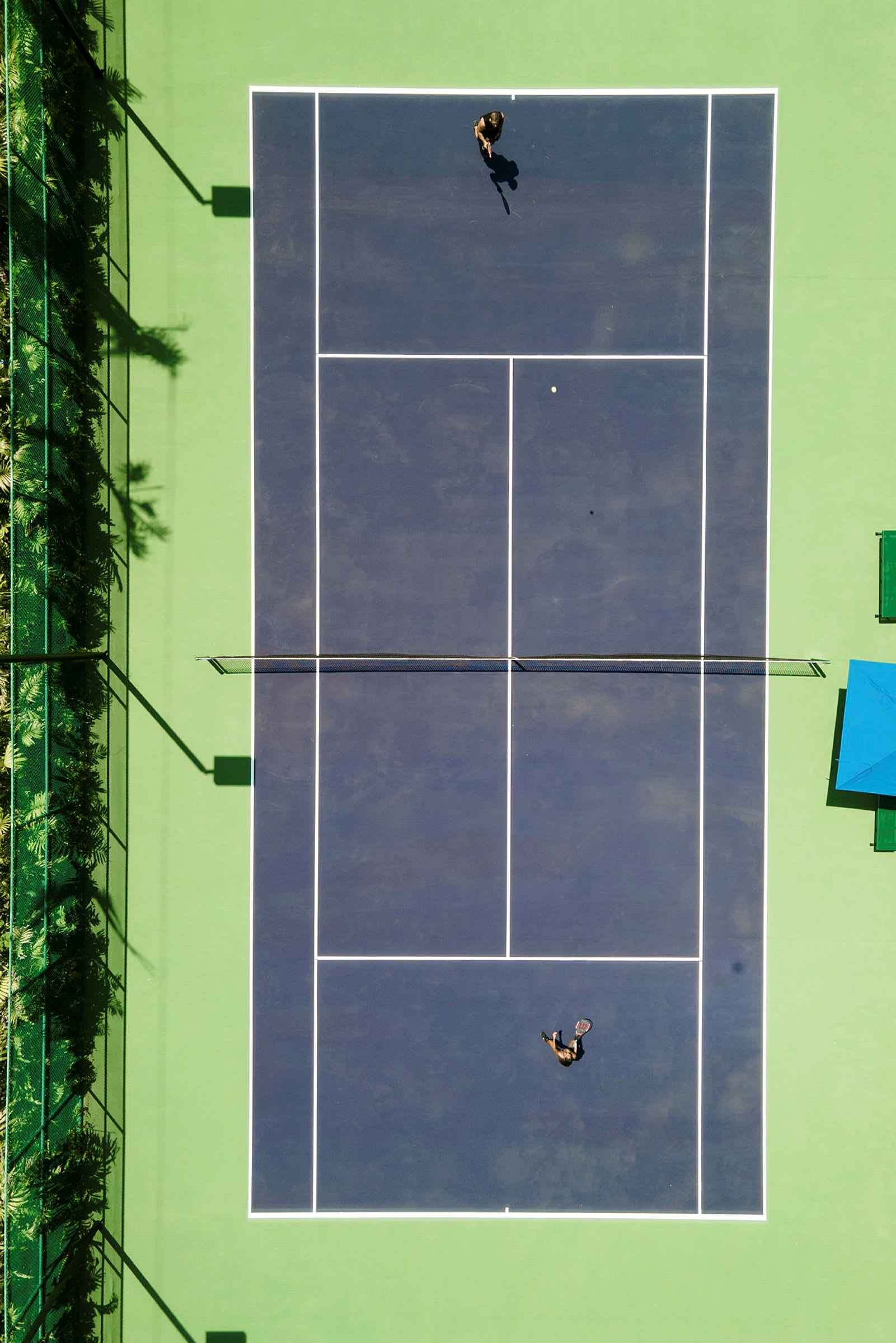 Luftfoto av en tennisbane med to personer som spiller tennis. (AI-generert tekst)
