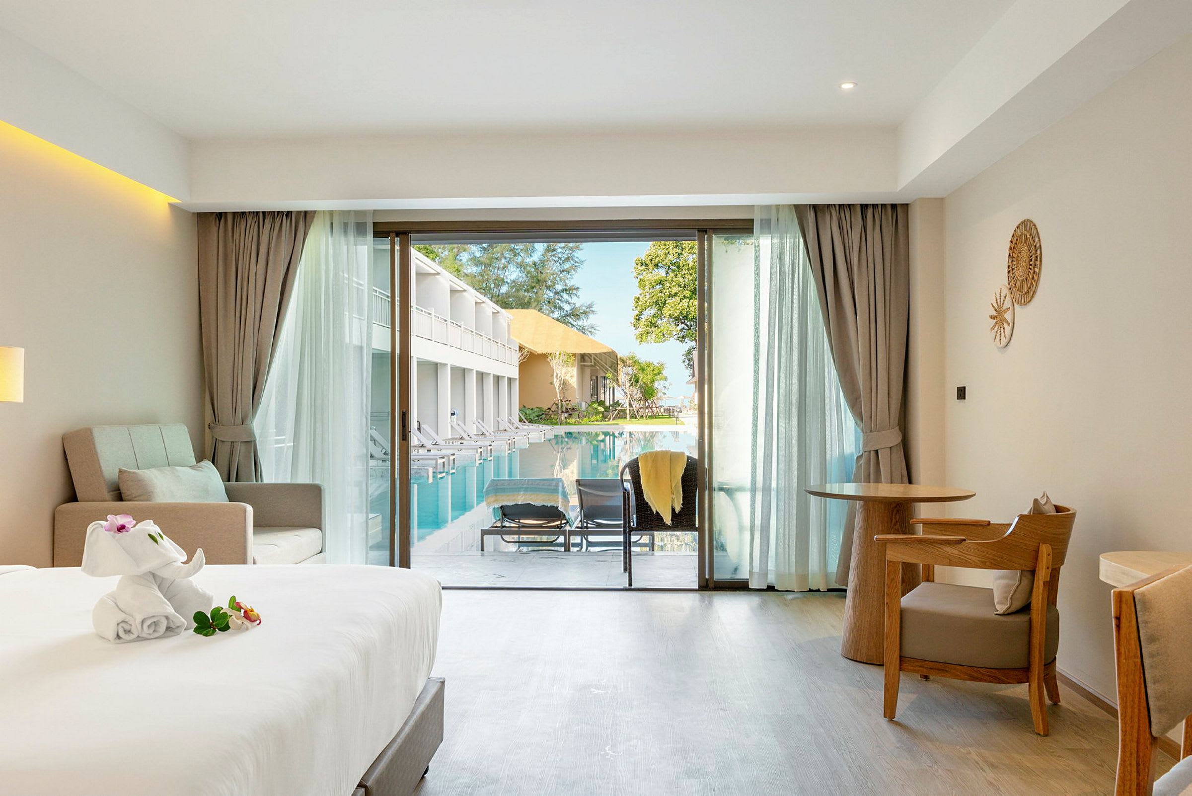 Hotellrom med balkong som vender ut mot et svømmebasseng. (AI-generert tekst)