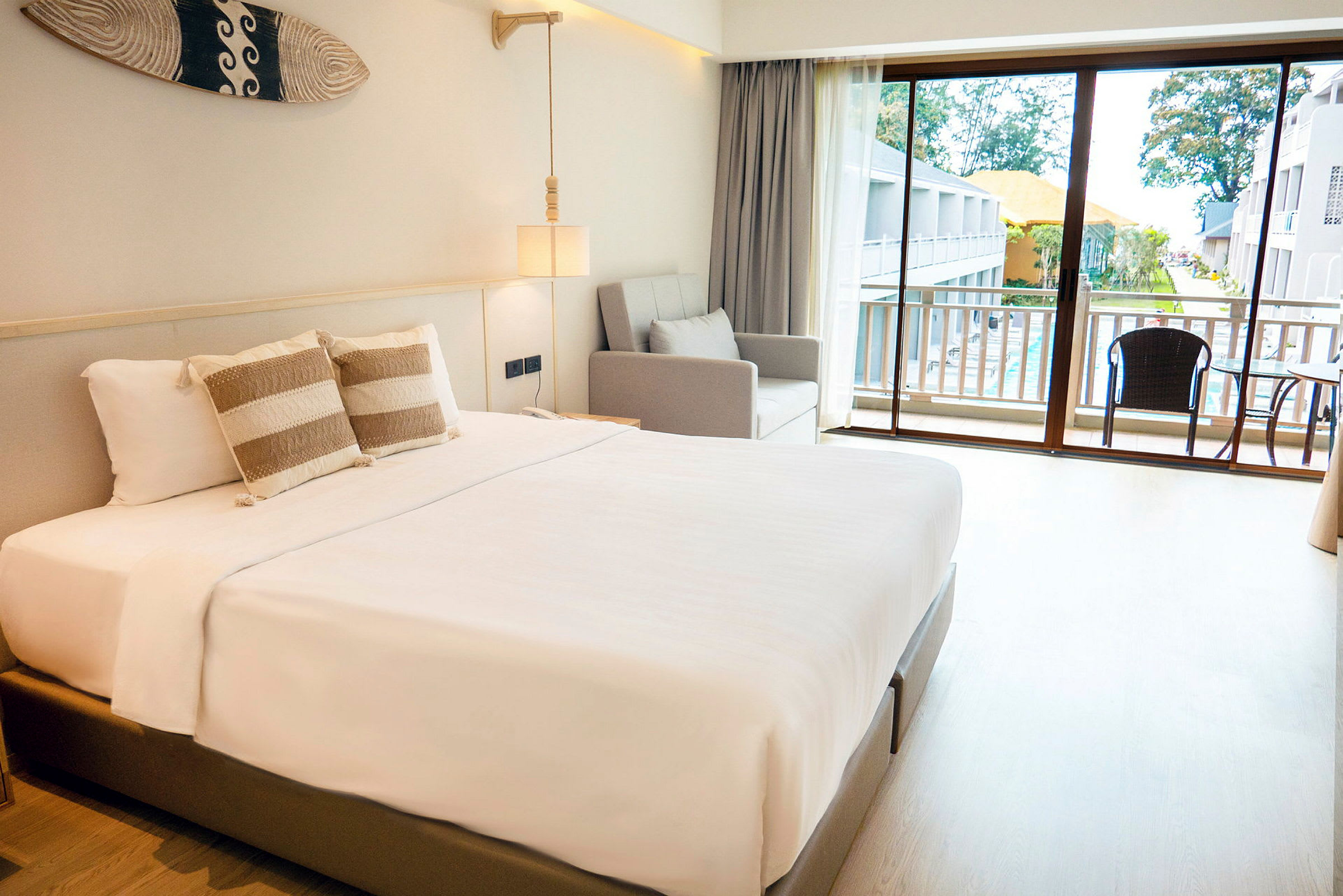 Et hotellrom med en dobbeltseng, sofa og balkong med utsikt. (AI-generert tekst)