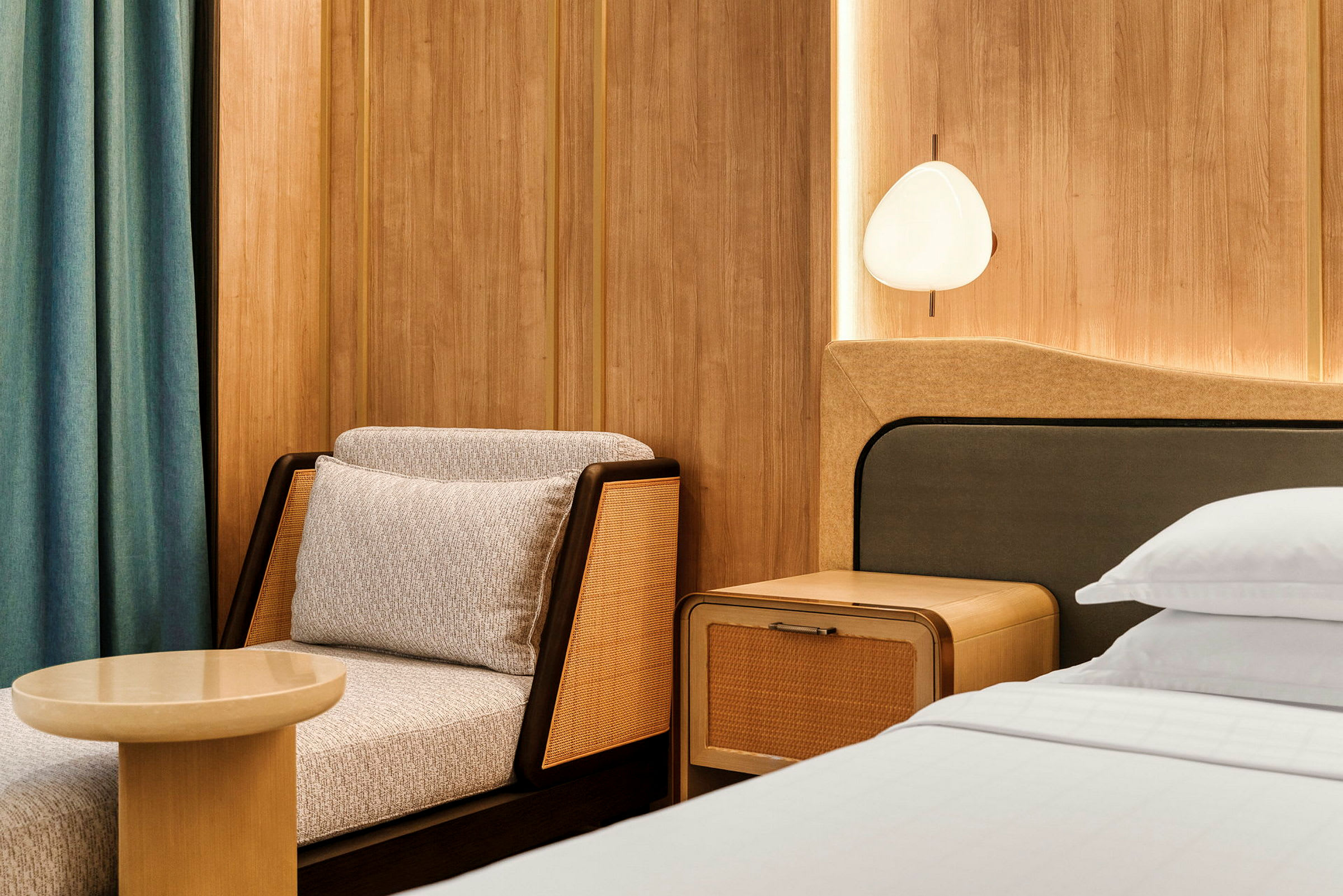 Sitteområde og en del av en seng på et moderne hotellrom med trepaneler. (AI-generert tekst)