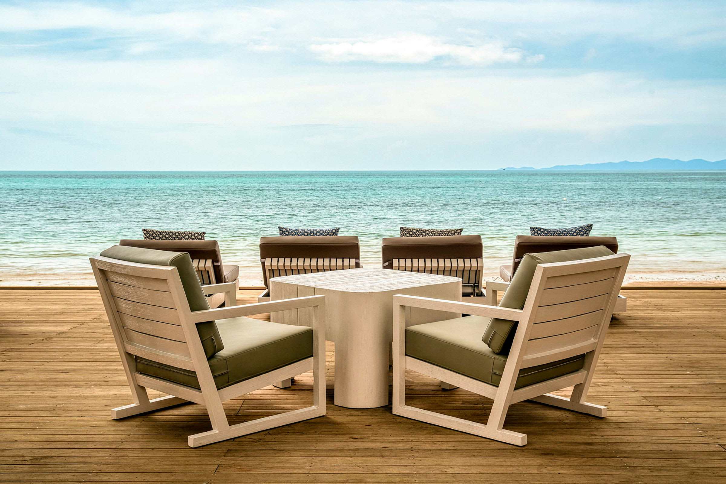 Tremøbler på en terrasse med utsikt over havet. (AI-generert tekst)