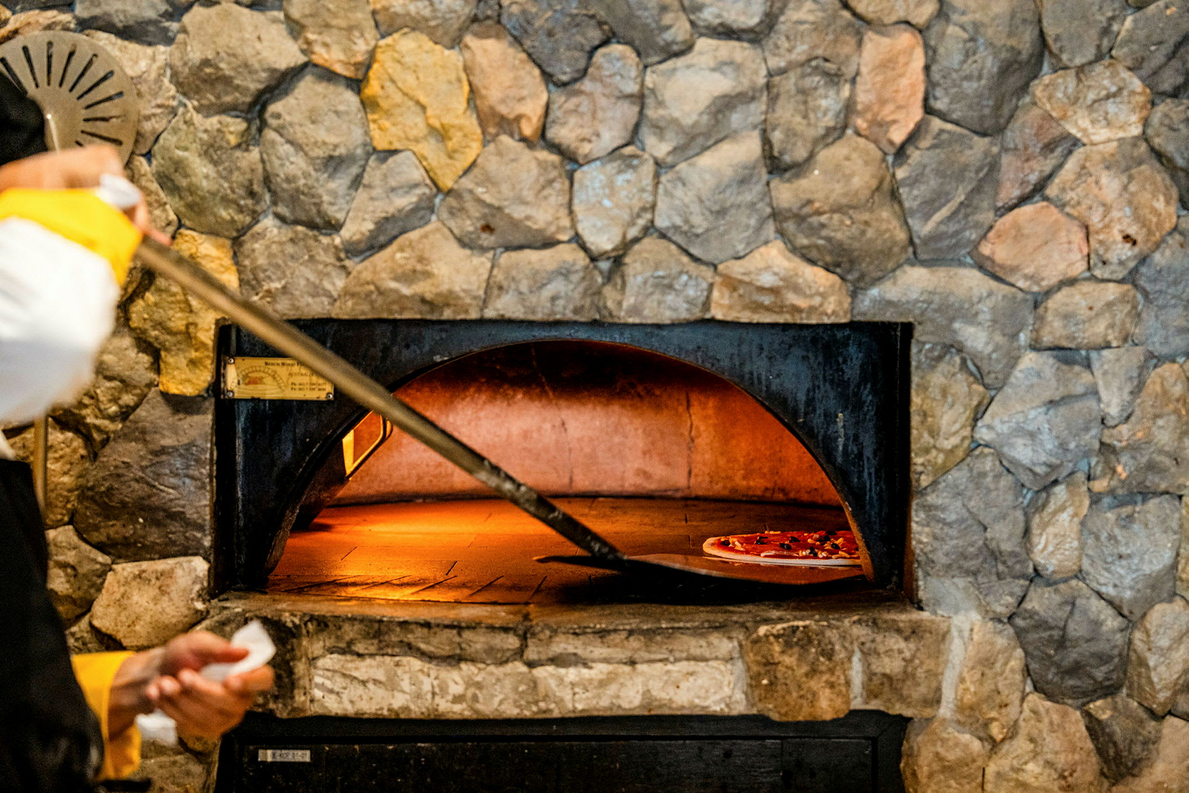 En steinovn med en pizza som stekes på en bakeflate. (AI-generert tekst)