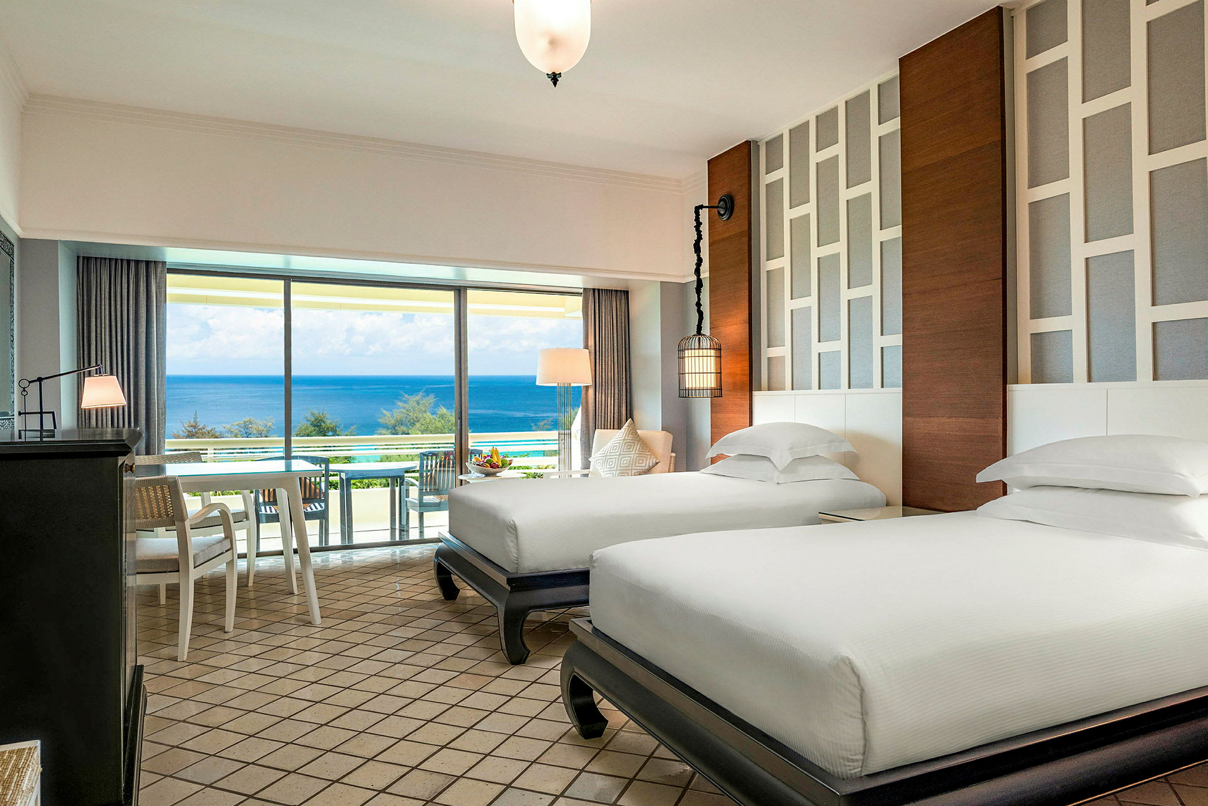 Et hotellrom med to separate enkeltsenger, moderne møbler og et lyst design. Et stort vindu med utsikt over havet. (AI-generert tekst)