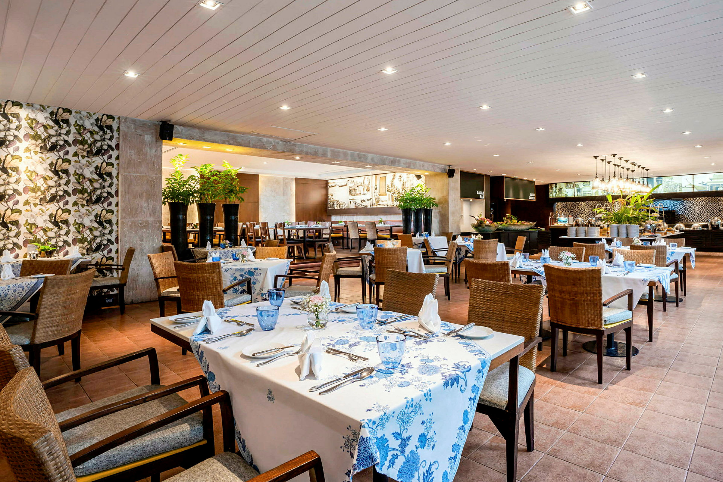 En restaurant med dekkede bord, blomstrede dekorasjoner og moderne møbler. (AI-generert tekst)