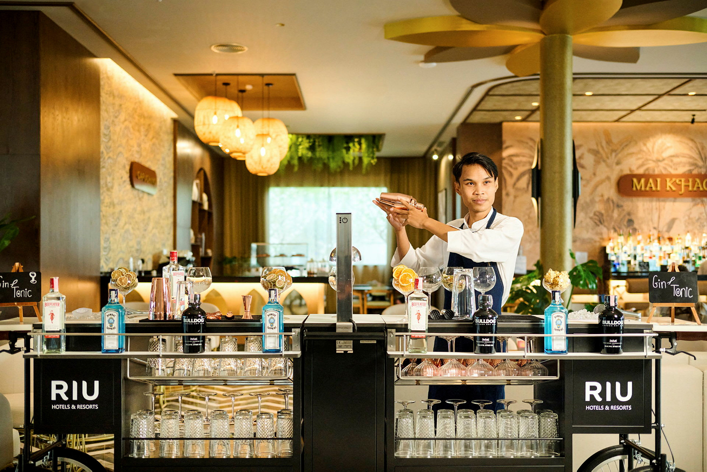 En bartender blander en drink ved en godt utstyrt barvogn i en elegant hotellomgivelse. (AI-generert tekst)