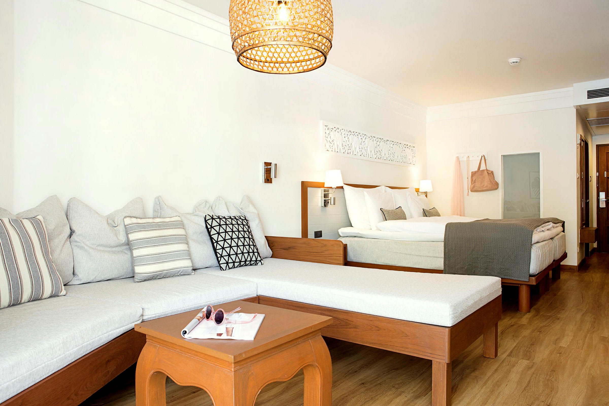Et hotellrom med en sofa, et bord og en dobbeltseng. (AI-generert tekst)