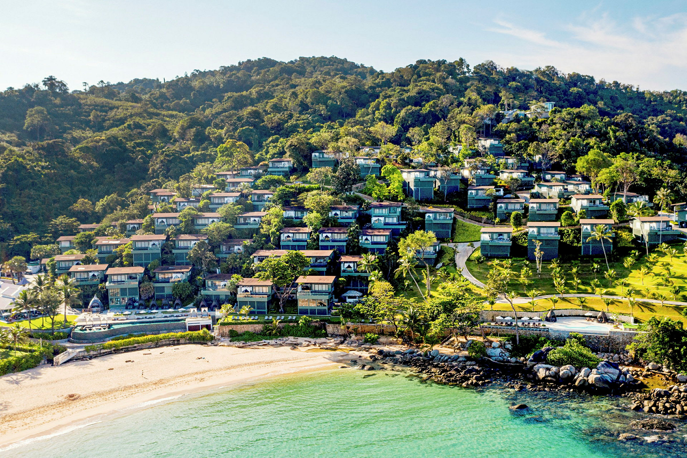 Hotellbygningene omgitt av grøntområder og nær stranden. (AI-generert tekst)