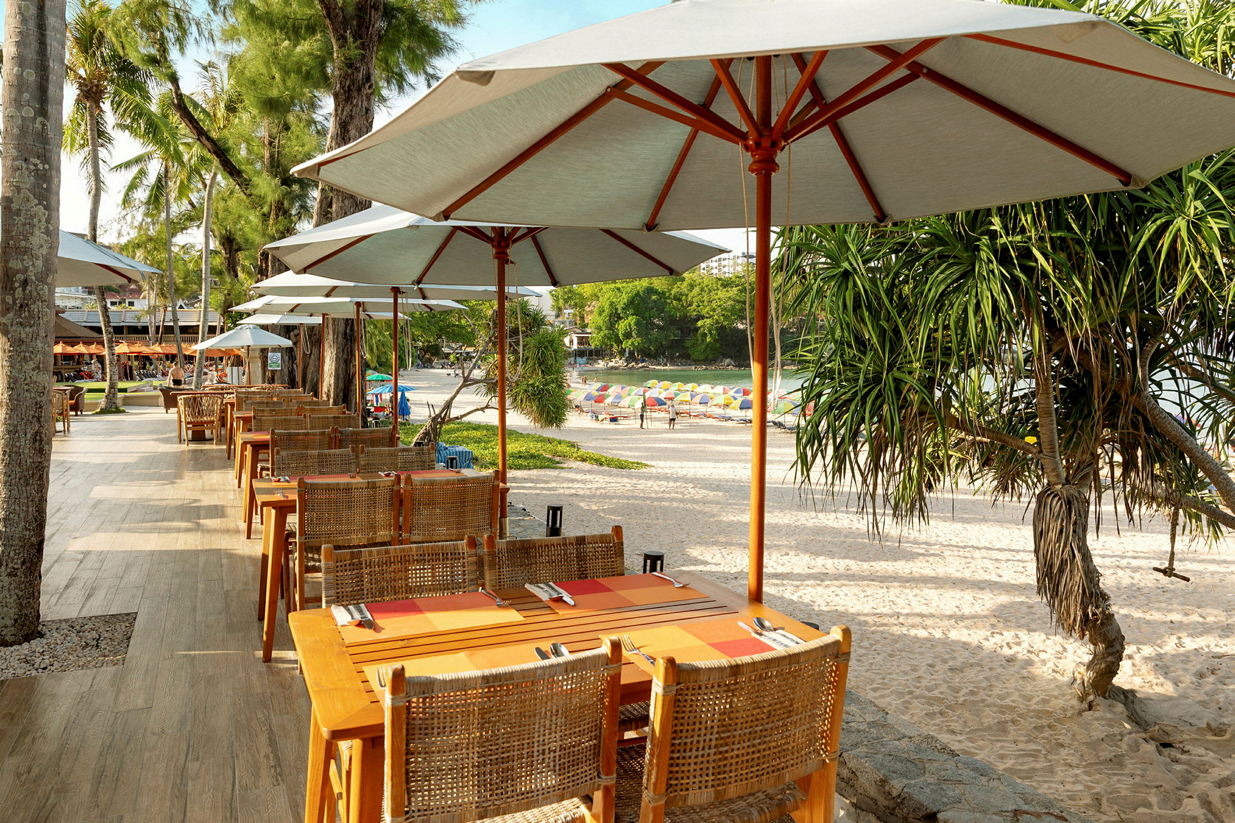 Strandrestaurant med bord og stoler under parasoller, med utsikt over stranden. (AI-generert tekst)