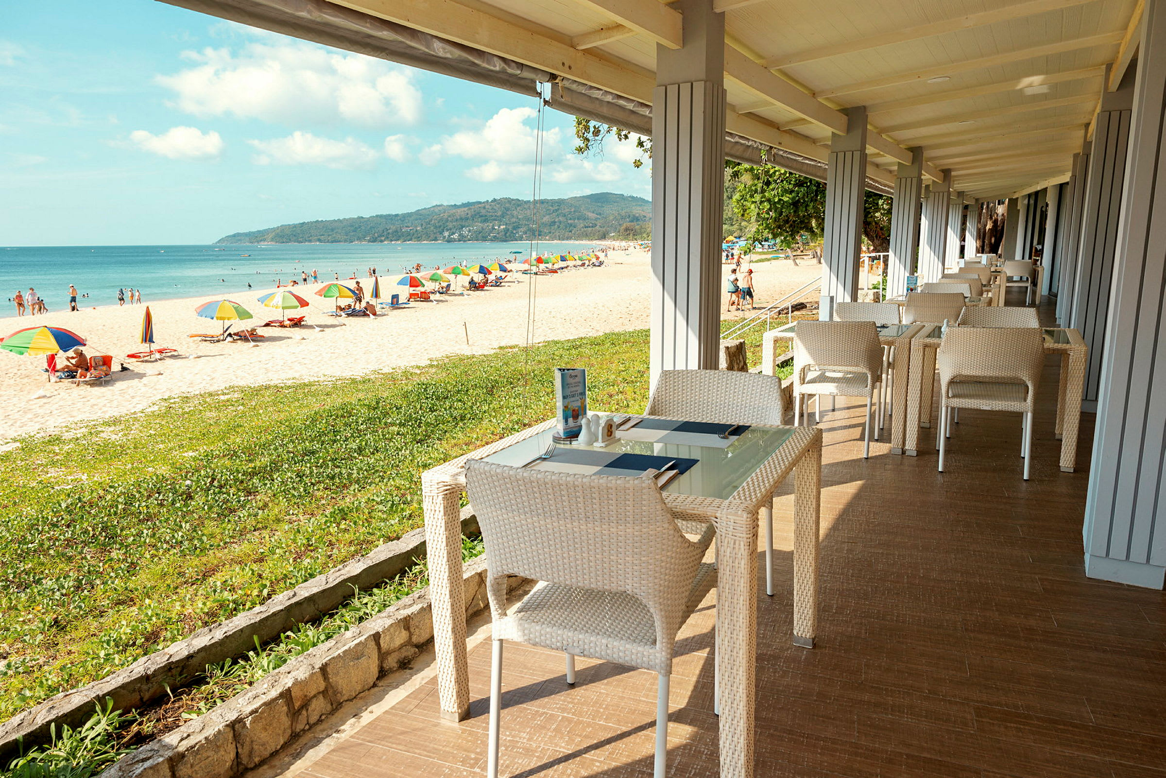 Restaurant med havutsikt nær en strand med parasoller. (AI-generert tekst)