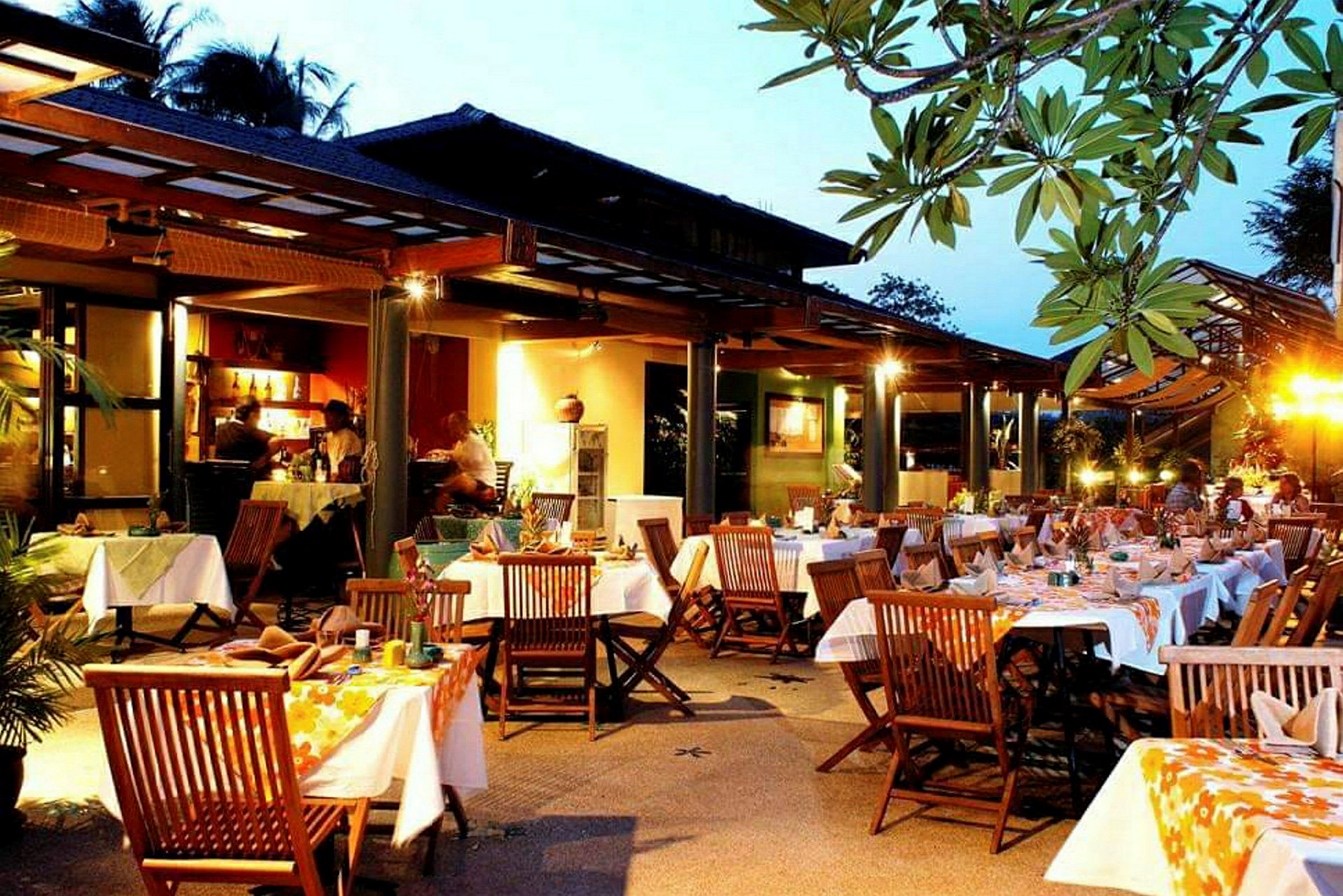 Kveldsstemning ved en restaurant med bord, stoler og dekorerte duker. (AI-generert tekst)
