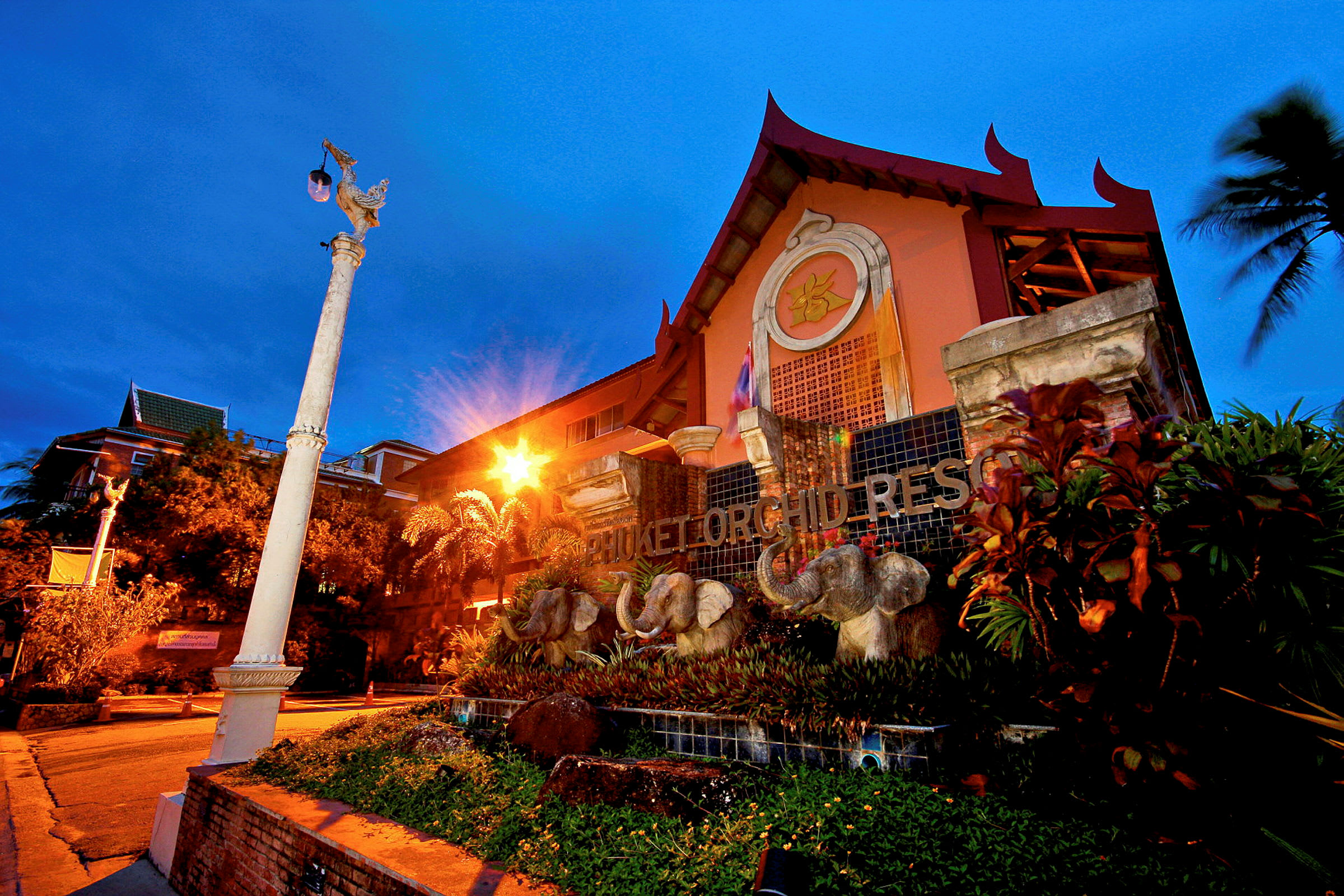 Utsiden av Phuket Orchid Resort med elefantdekorasjoner foran bygningen. (AI-generert tekst)