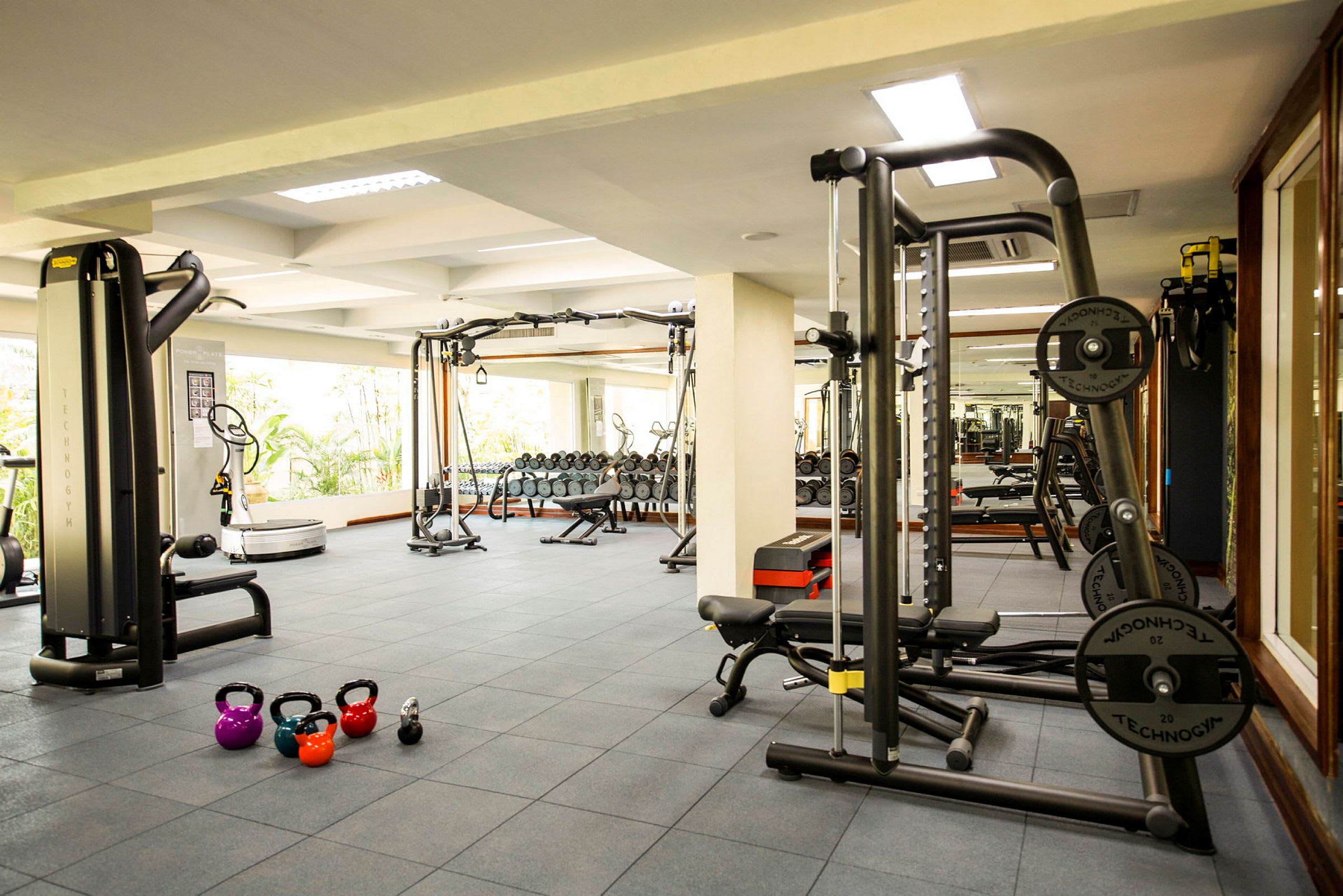 Et treningssenter med treningsapparater, frivekter og kettlebells på gulvet. (AI-generert tekst)