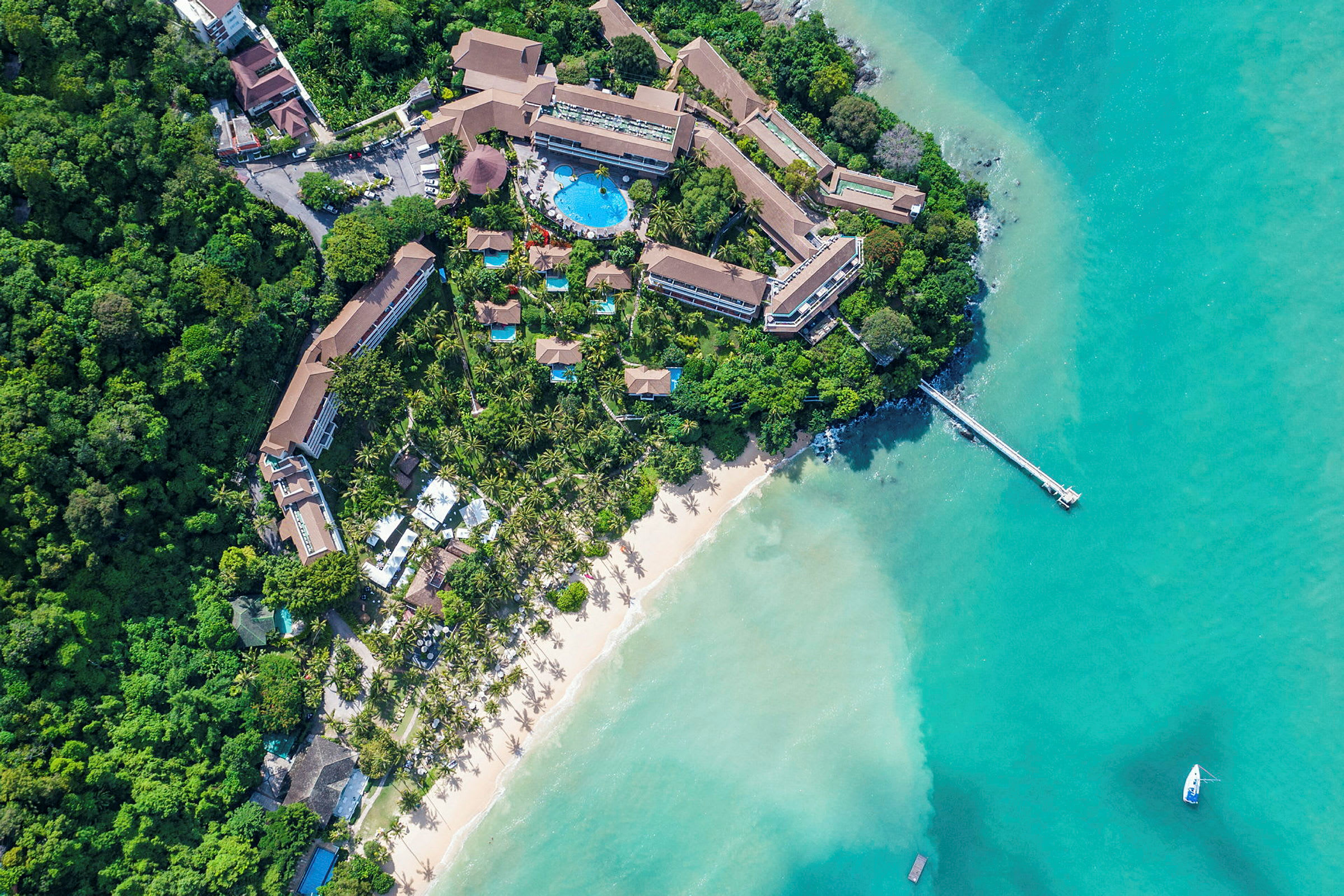 Flyfoto av en resort ved en sandstrand og turkist vann. (AI-generert tekst)