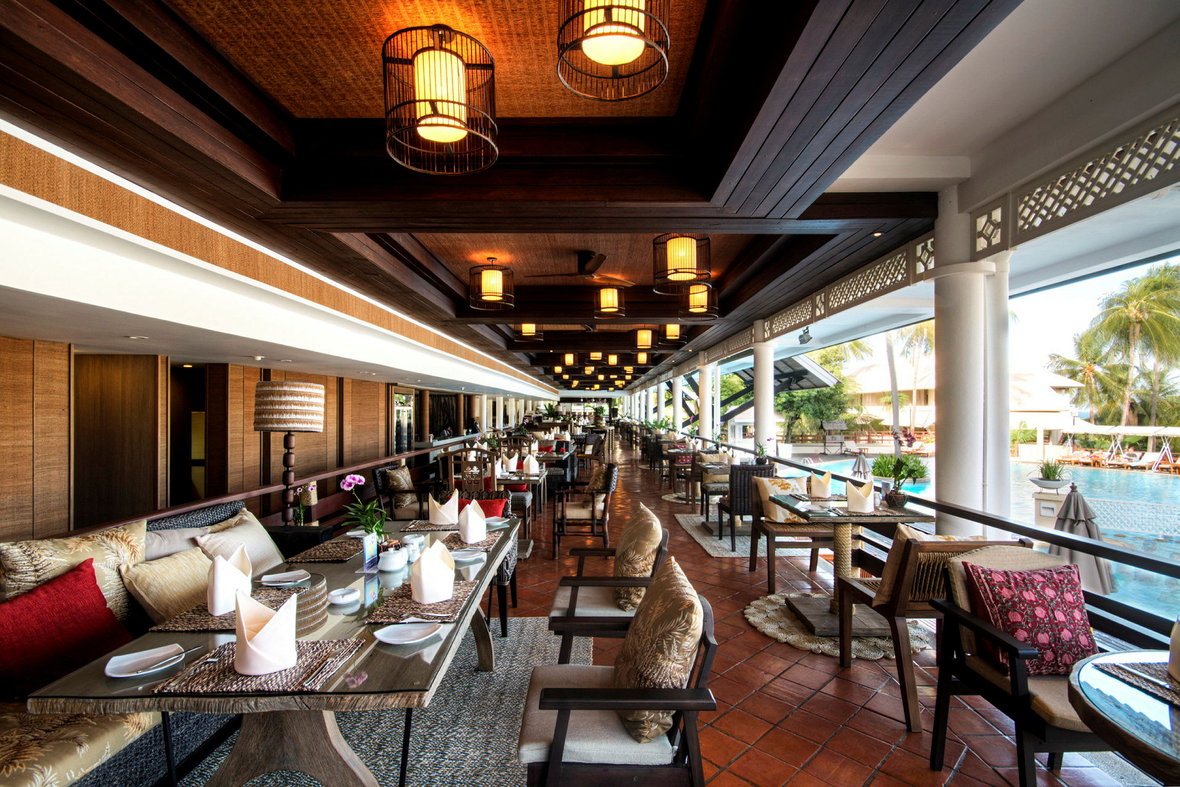 Bilde av en restaurant med sitteplasser, dekorerte bord og utsikt over et basseng. (AI-generert tekst)