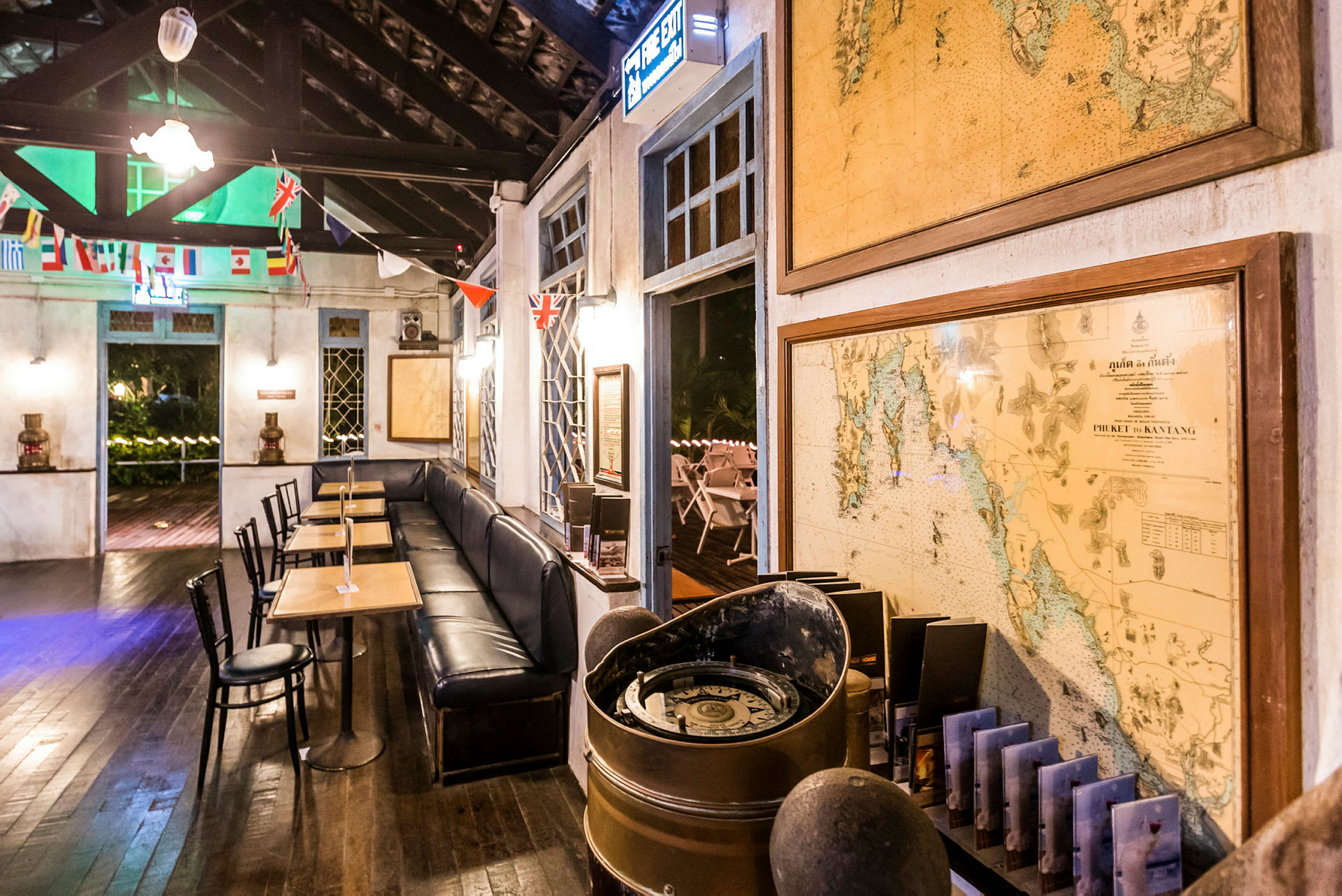Interiør av en kafé med bord og stoler, dekorert med kart og flagg. (AI-generert tekst)