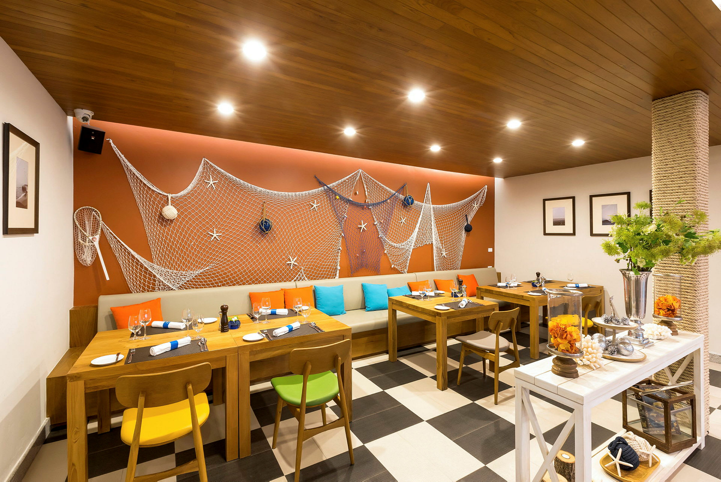 Restaurant med maritim dekor, trebord og fargerike stoler. (AI-generert tekst)