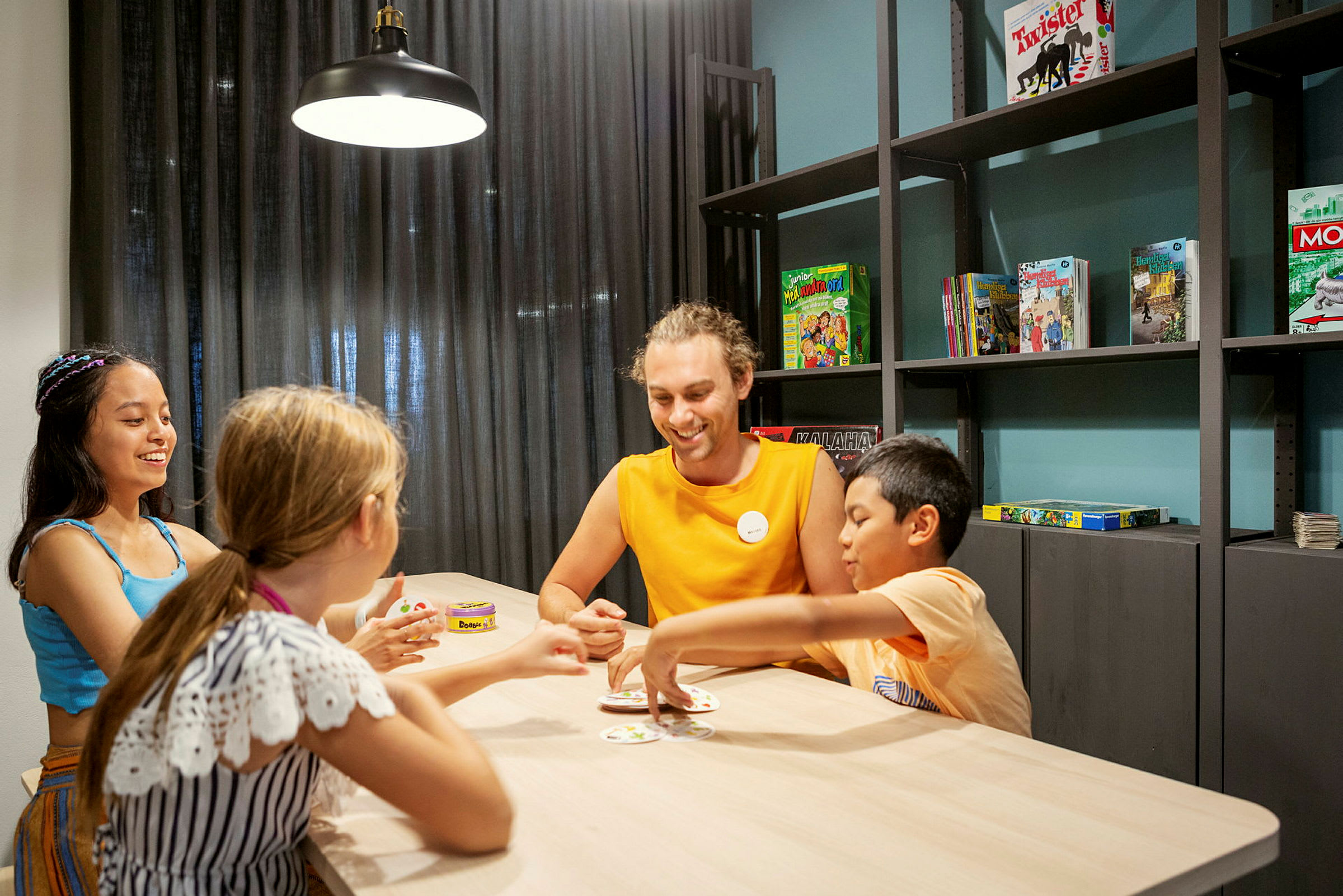 Flere barn sitter ved et bord og spiller et kortspill. (AI-generert tekst)