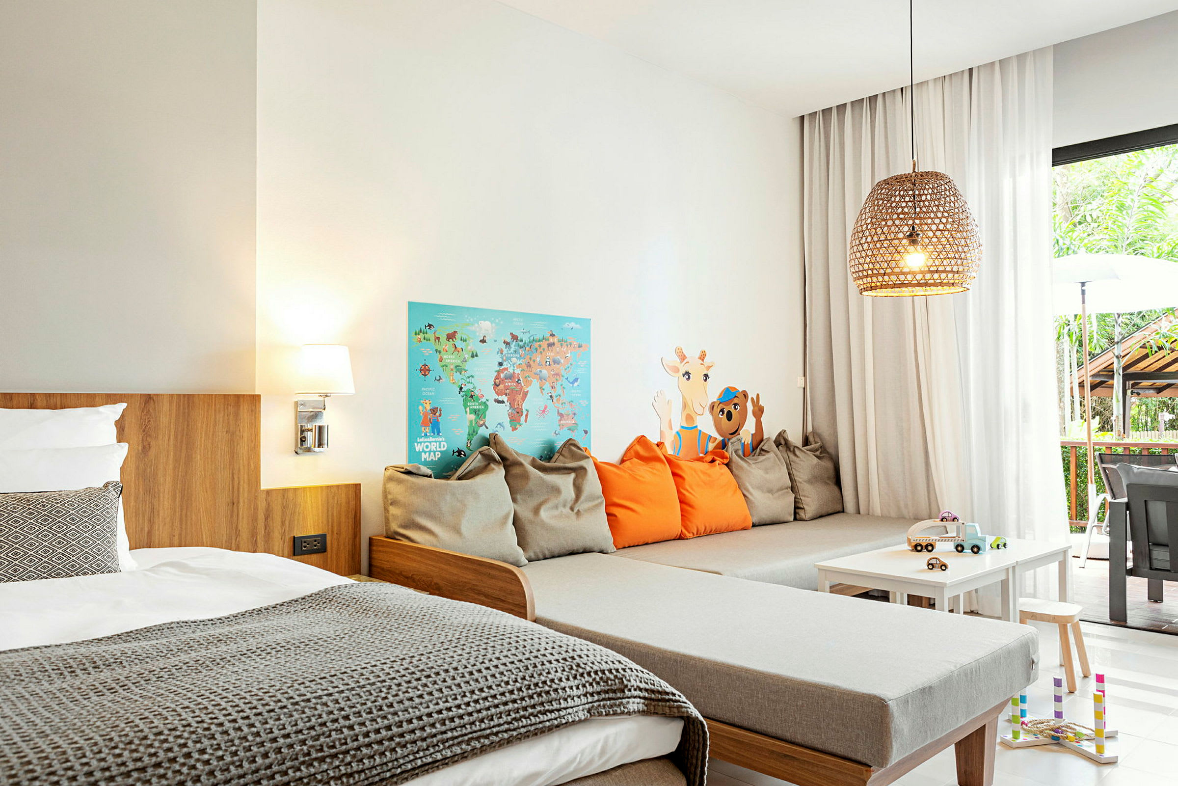 Interiør av et moderne hotellrom med seng, sittegruppe og leker på et bord. (AI-generert tekst)