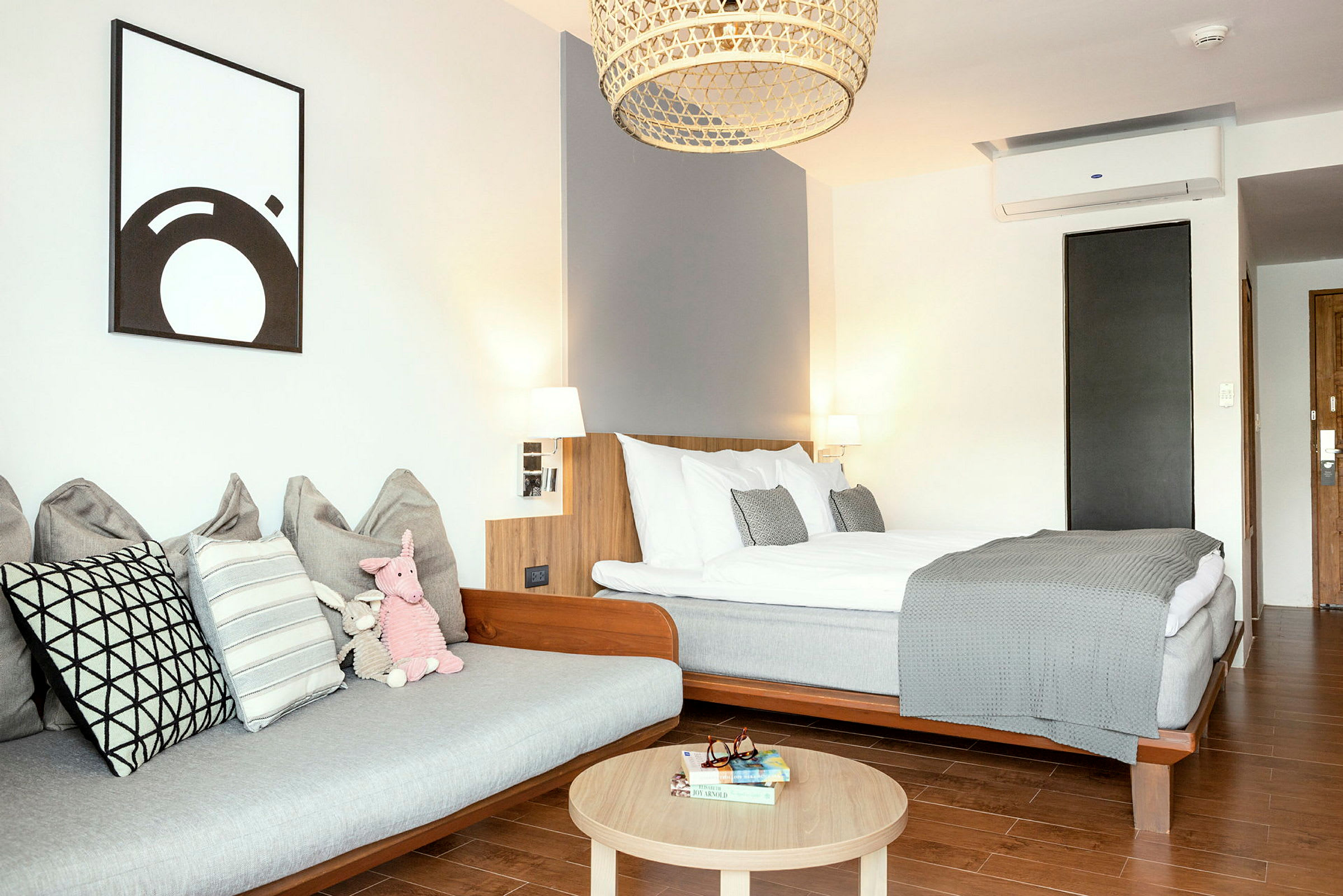 Et moderne hotellrom med en seng, en sofa og et trebord. (AI-generert tekst)