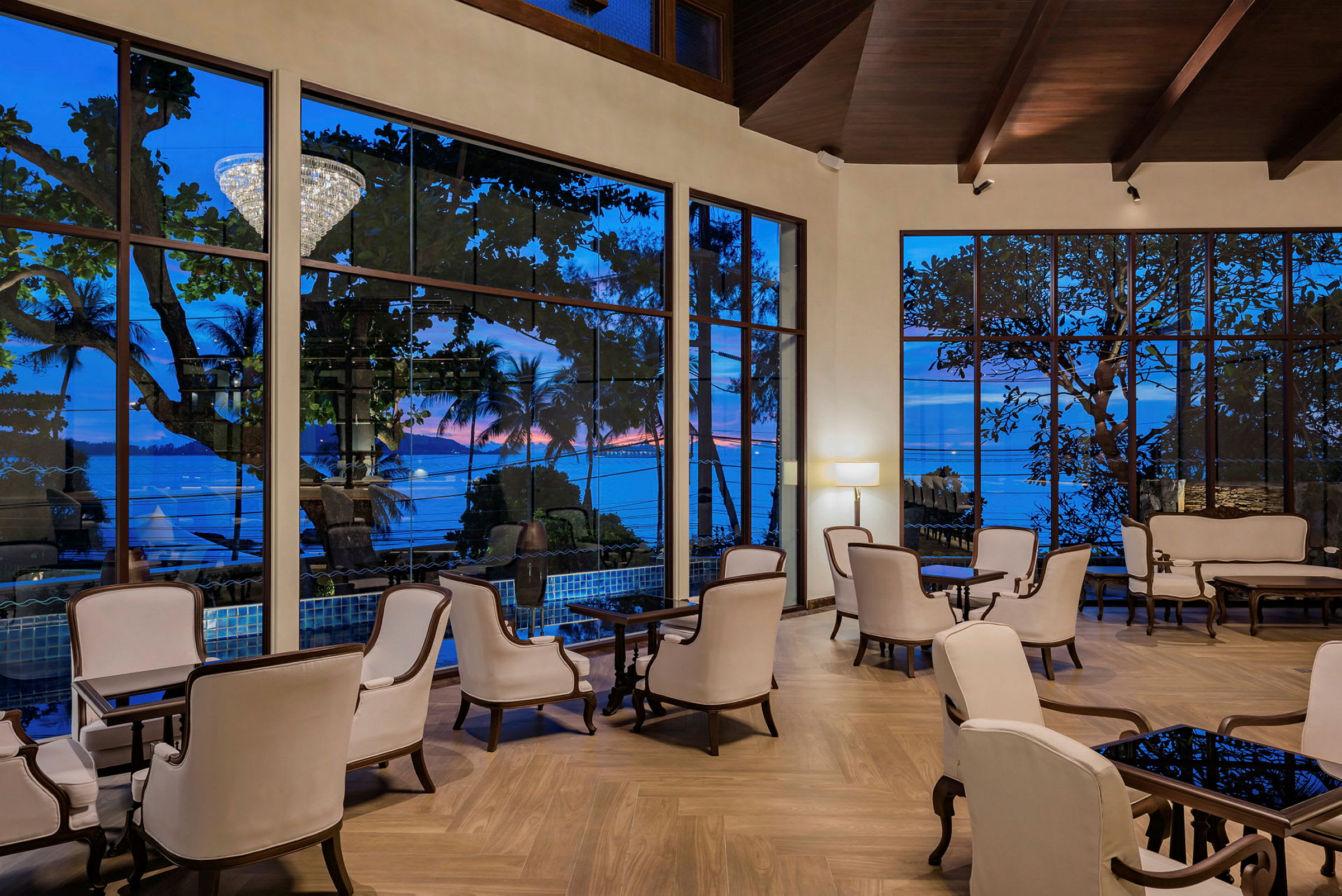 En elegant hotellobby med hvite lenestoler og store vinduer med utsikt mot havet. (AI-generert tekst)
