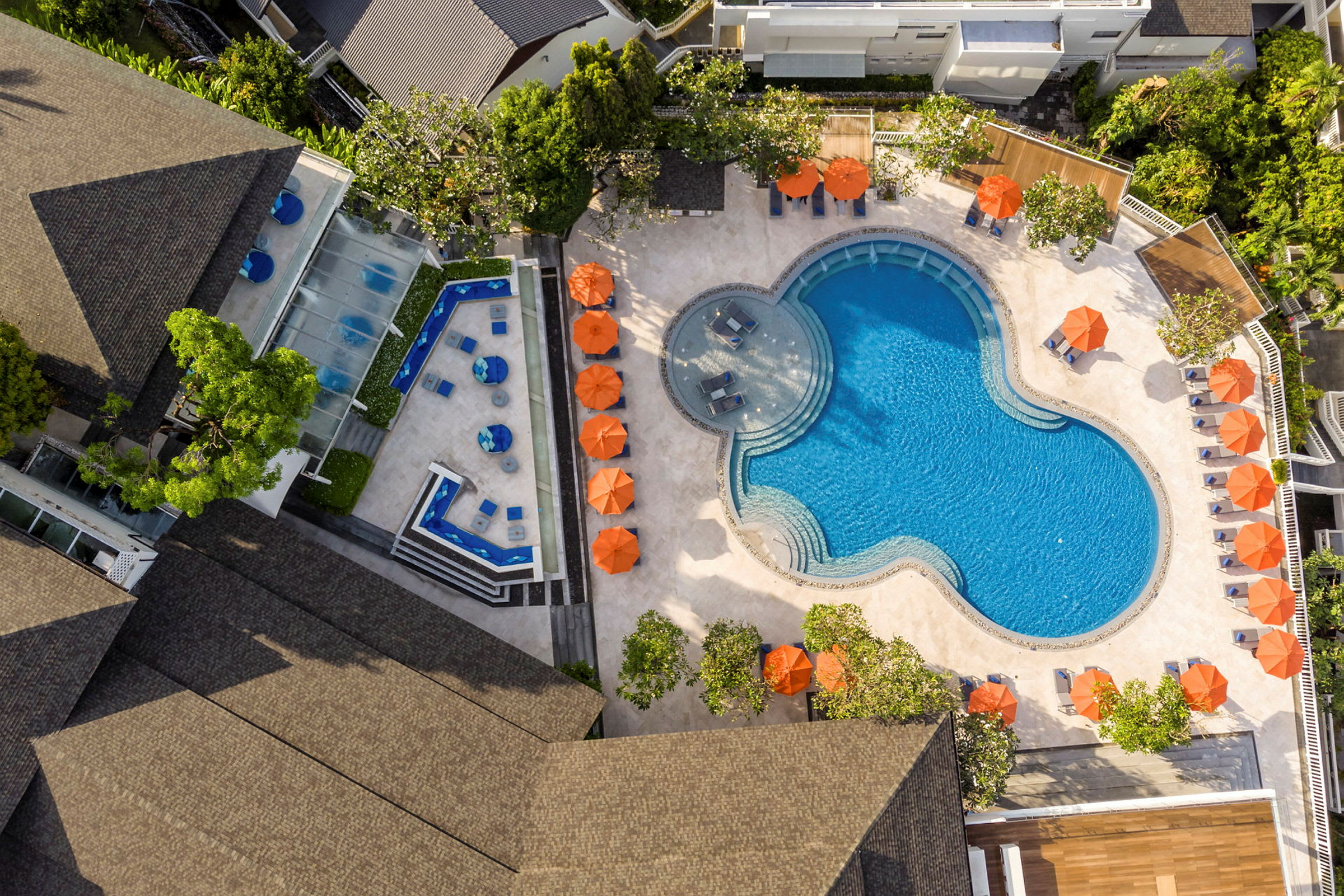 Flyfoto av svømmebasseng og terrasse med solsenger og parasoller. (AI-generert tekst)