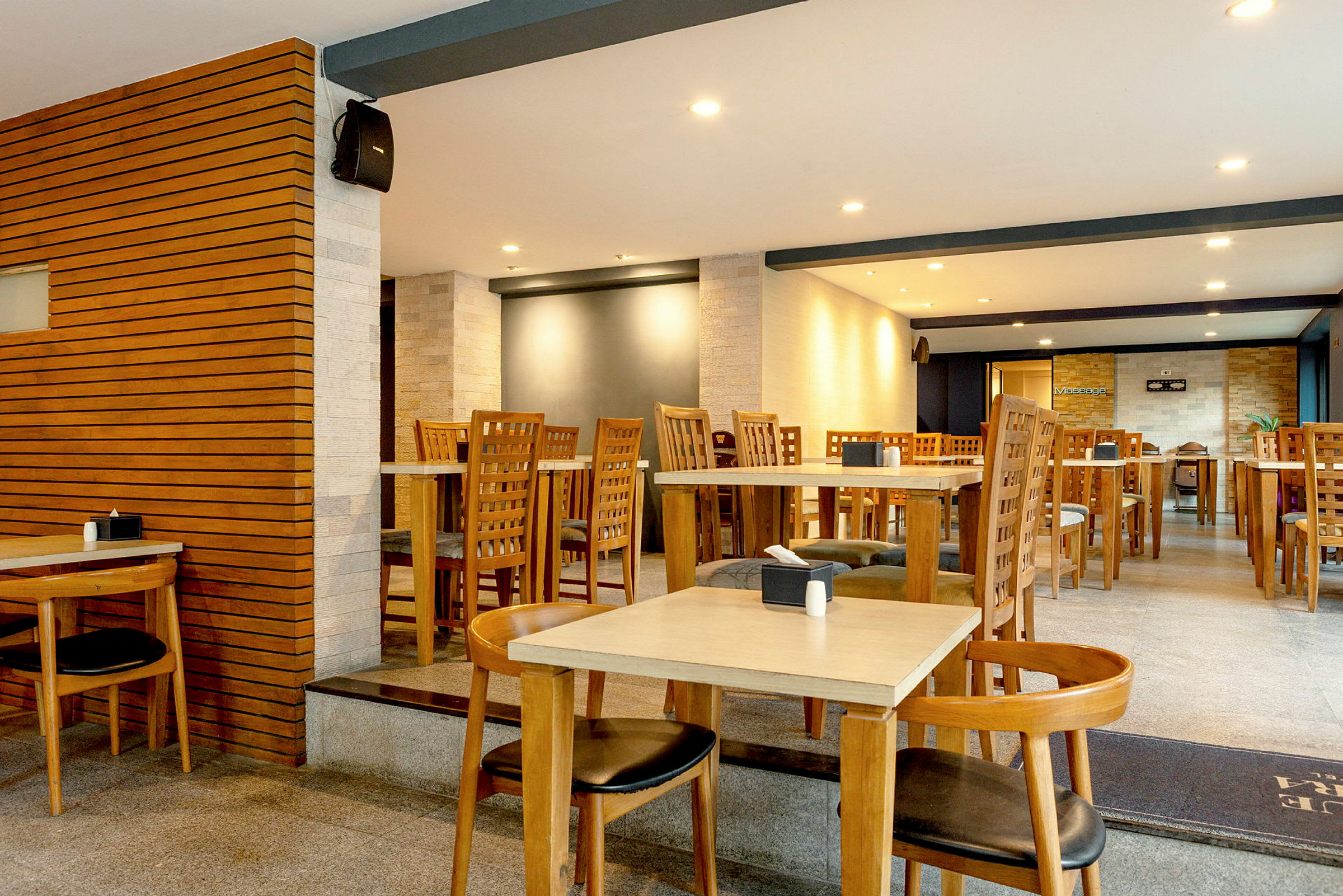 En restaurant med bord og stoler i tre samt moderne innredning. (AI-generert tekst)