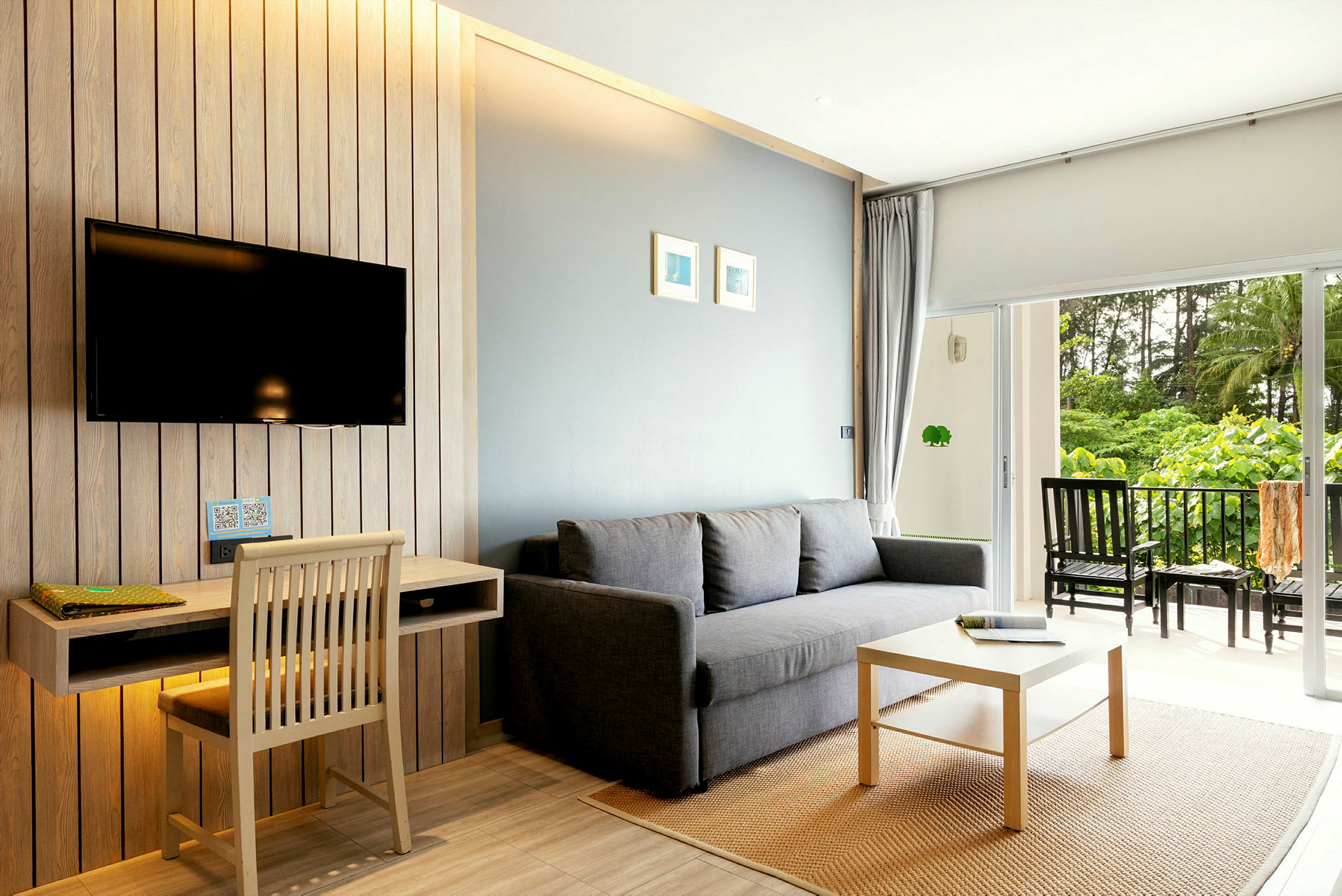 En moderne innredet stue med en grå sofa, et trebord og en balkong med sittemøbler. (AI-generert tekst)