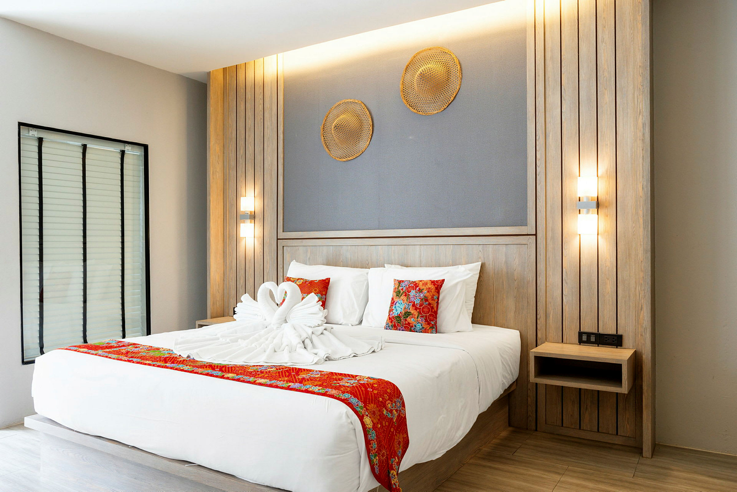 Moderne hotellrom med en dobbeltseng dekorert med håndklær formet som svaner og røde detaljer. (AI-generert tekst)