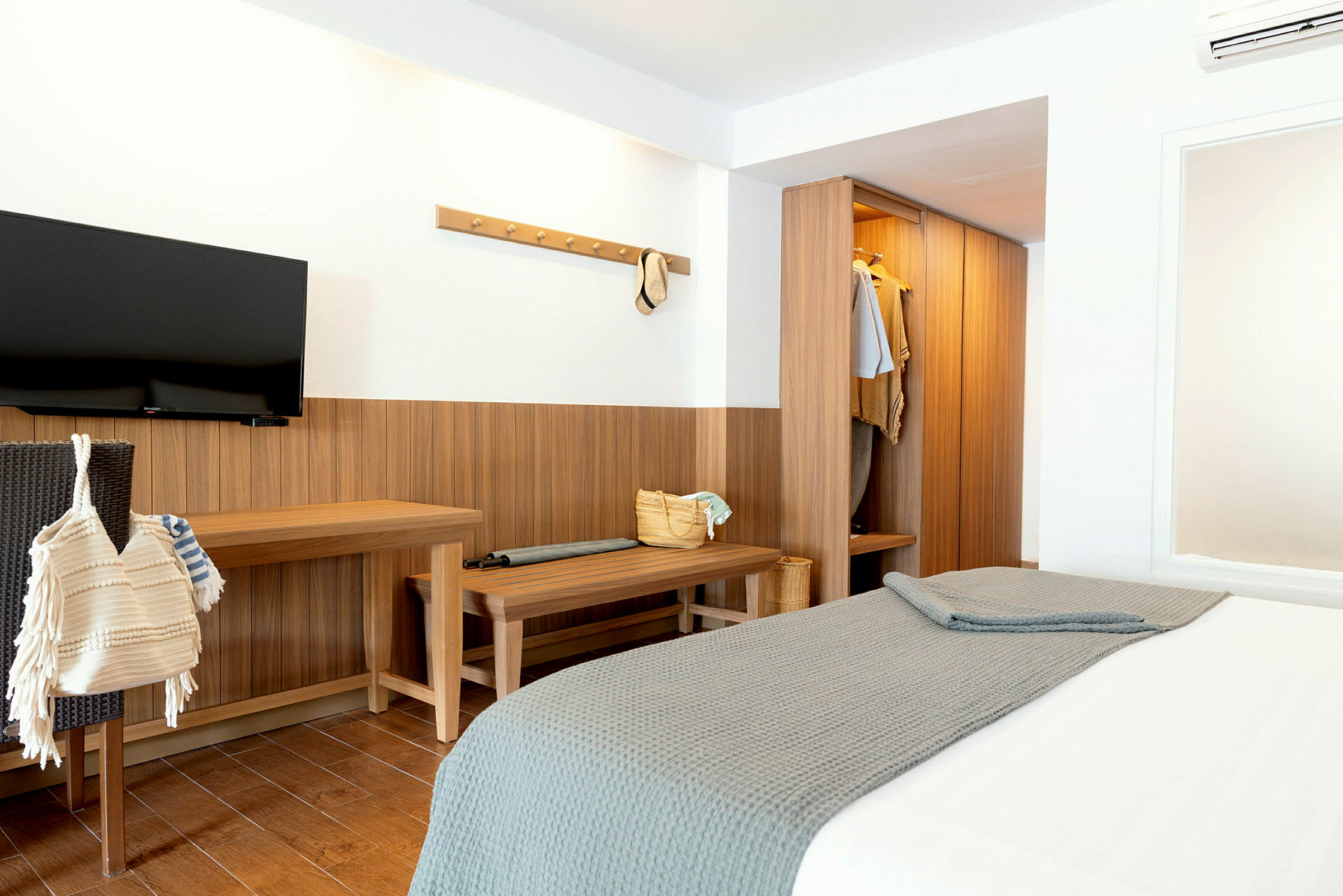 Et hotellrom med en seng, garderobe og en TV på veggen. (AI-generert tekst)