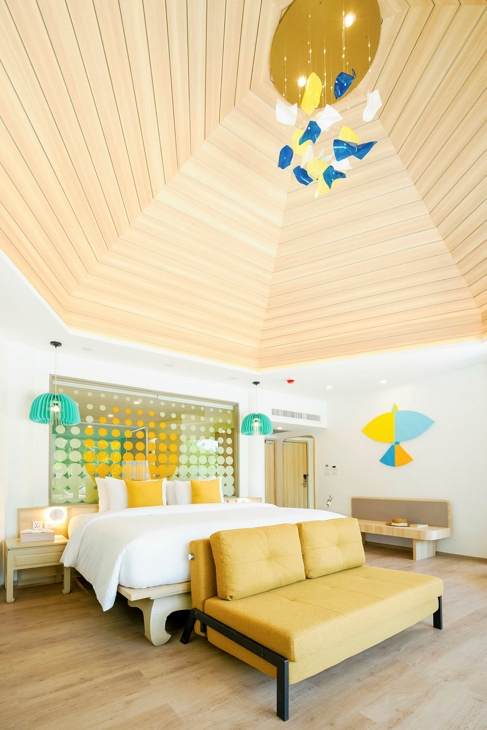 Et lyst og moderne hotellrom med en stor seng, gul sofa og unike dekorative elementer. (AI-generert tekst)
