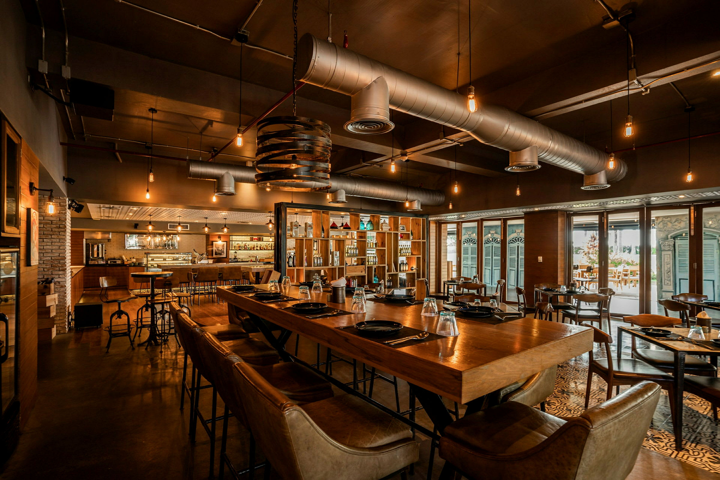 Restaurant med moderne innredning, trebord og stoler, opplyst med hengende lamper. (AI-generert tekst)