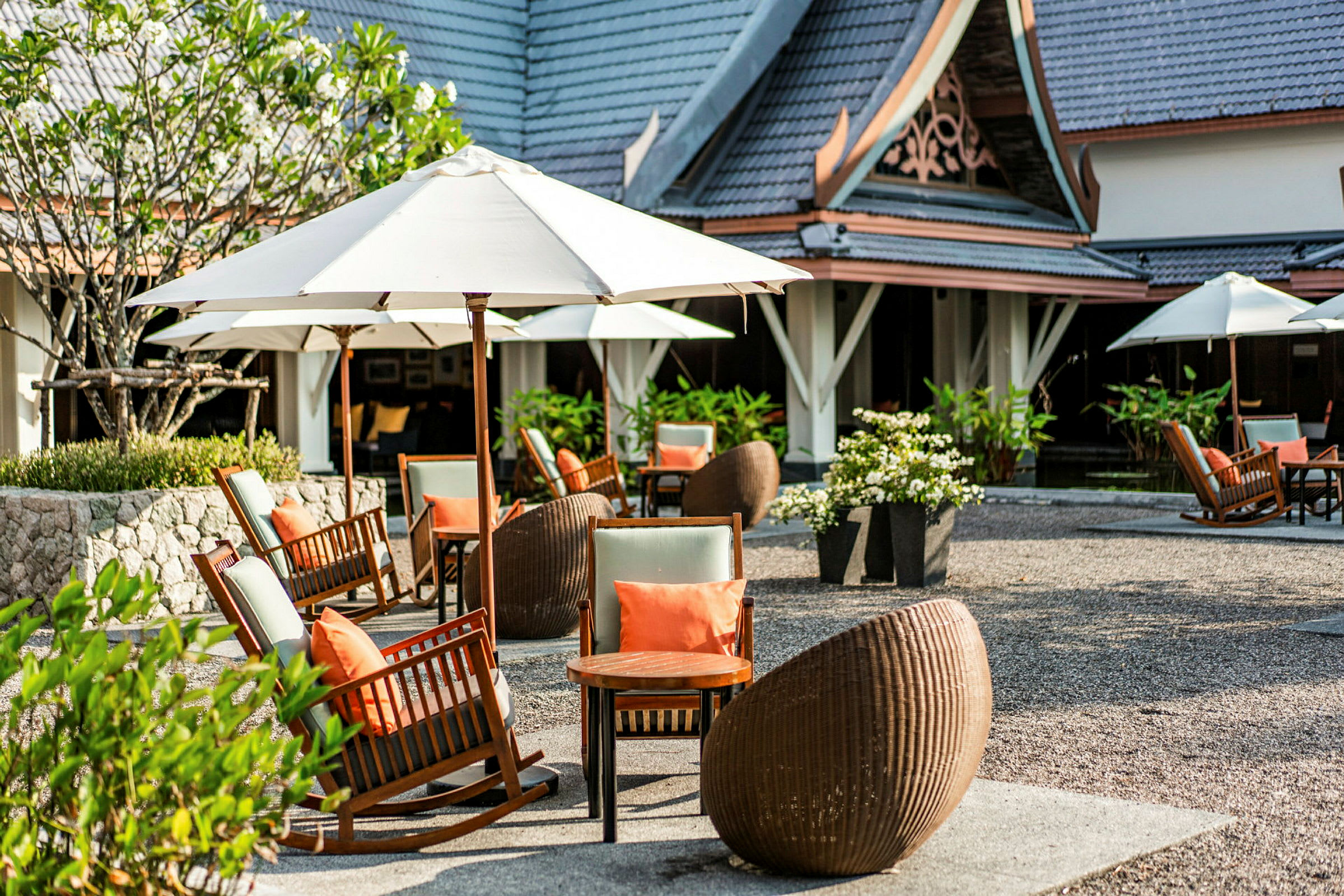 En terrasse ved en bygning med stoler, bord og parasoller. (AI-generert tekst)