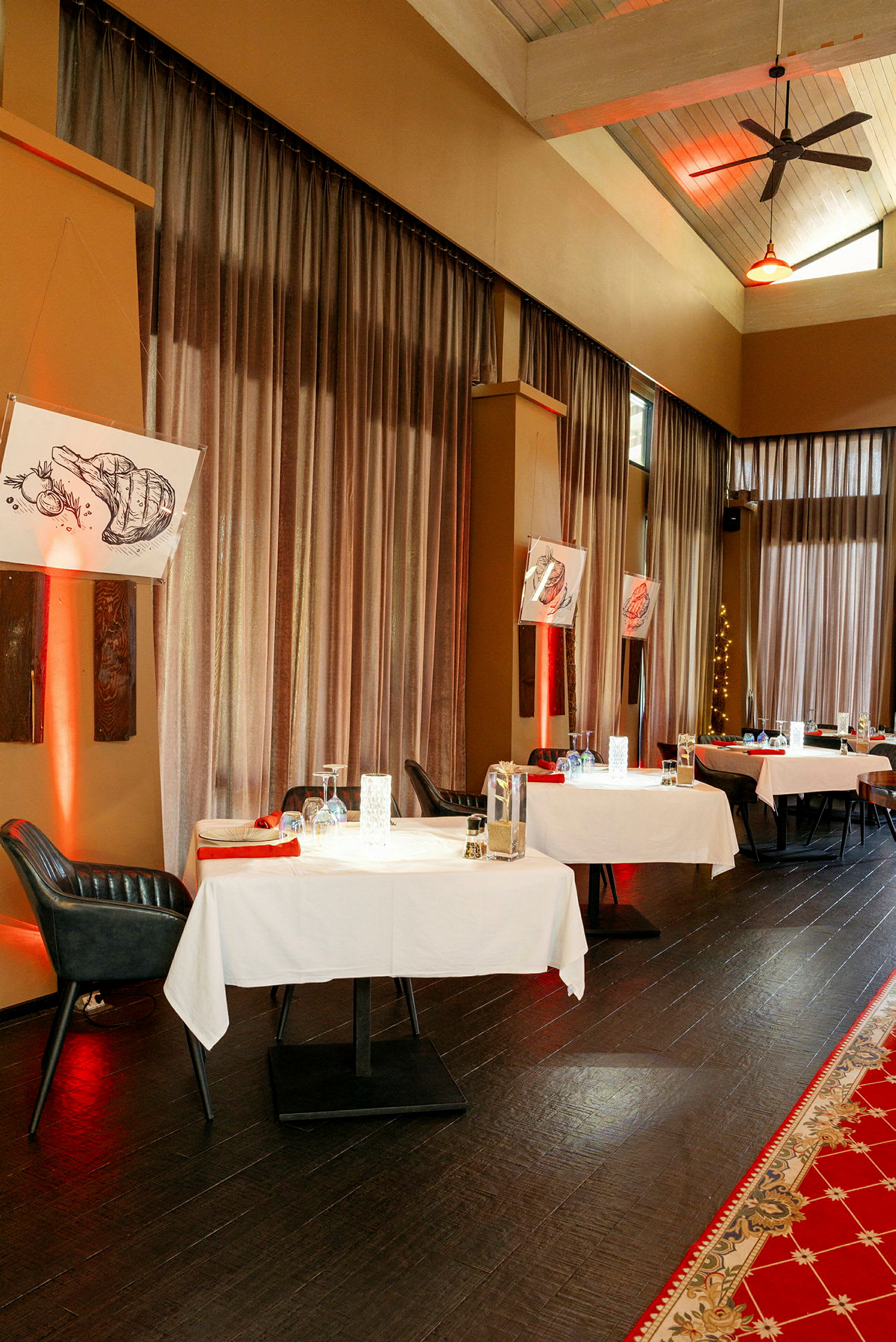 En restaurant med dekkede bord, røde servietter og dekorativ belysning. (AI-generert tekst)
