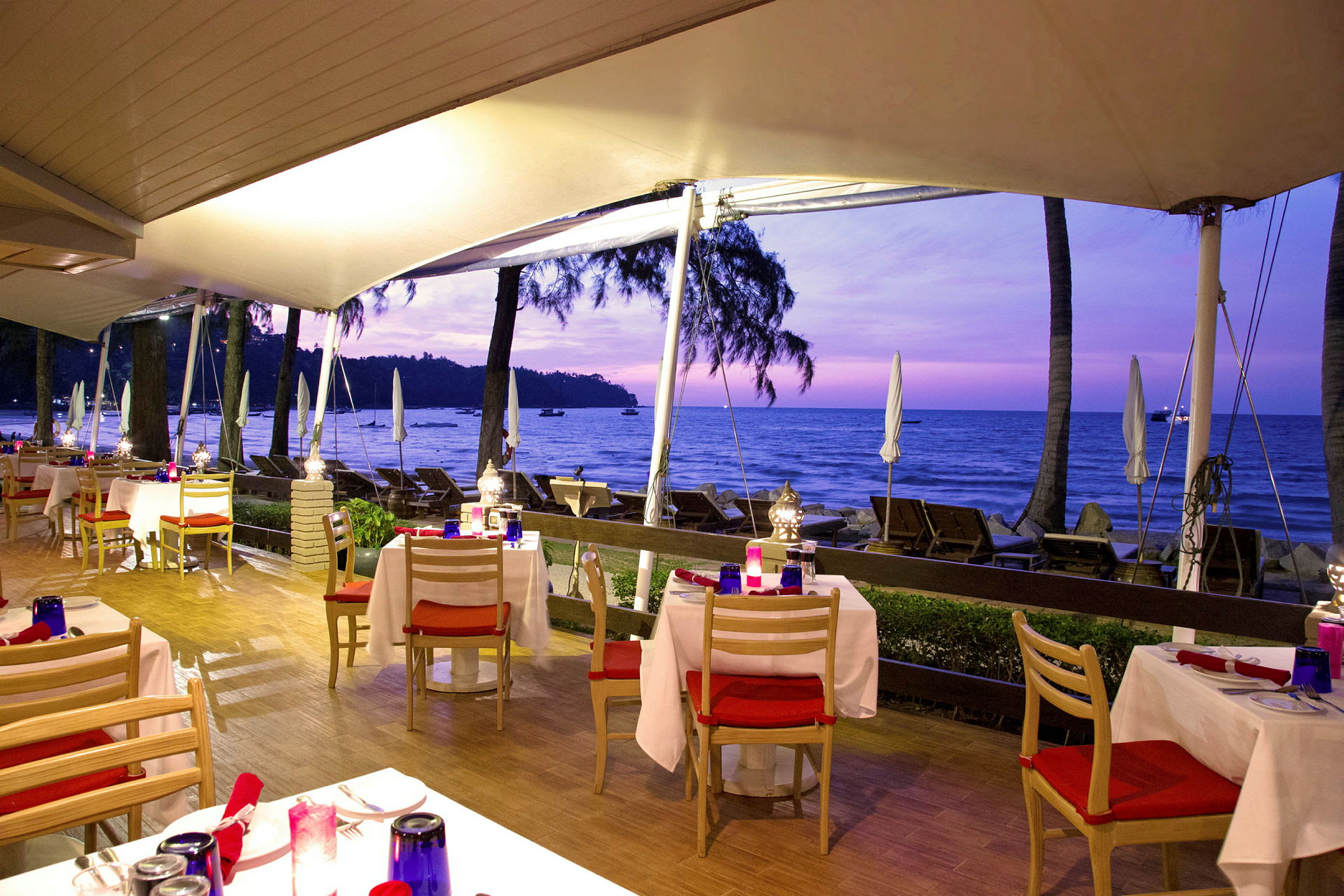 Restaurant med uteservering ved stranden i solnedgangen. (AI-generert tekst)
