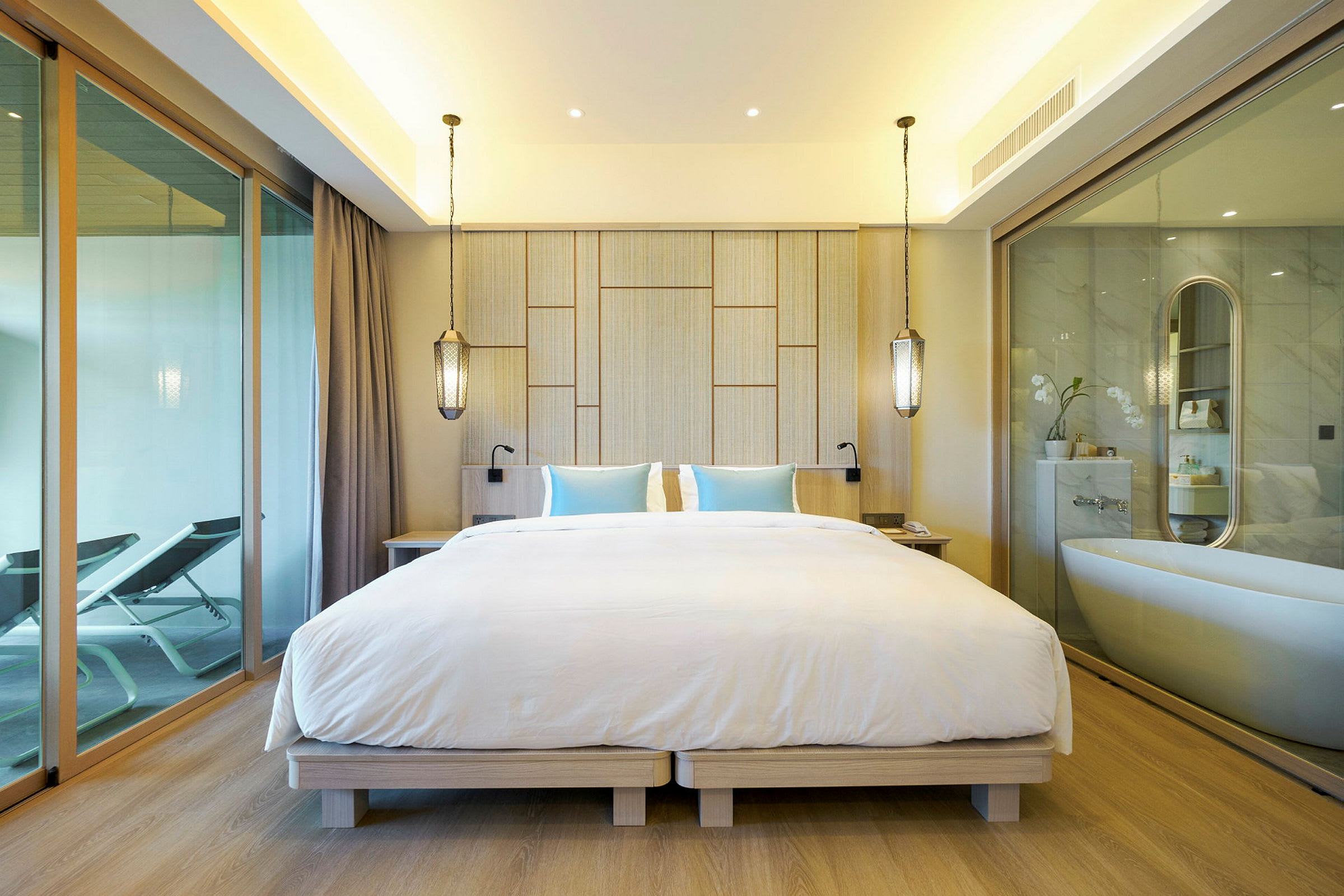 Moderne hotellrom med dobbeltseng og badekar synlig gjennom glassvegg. (AI-generert tekst)
