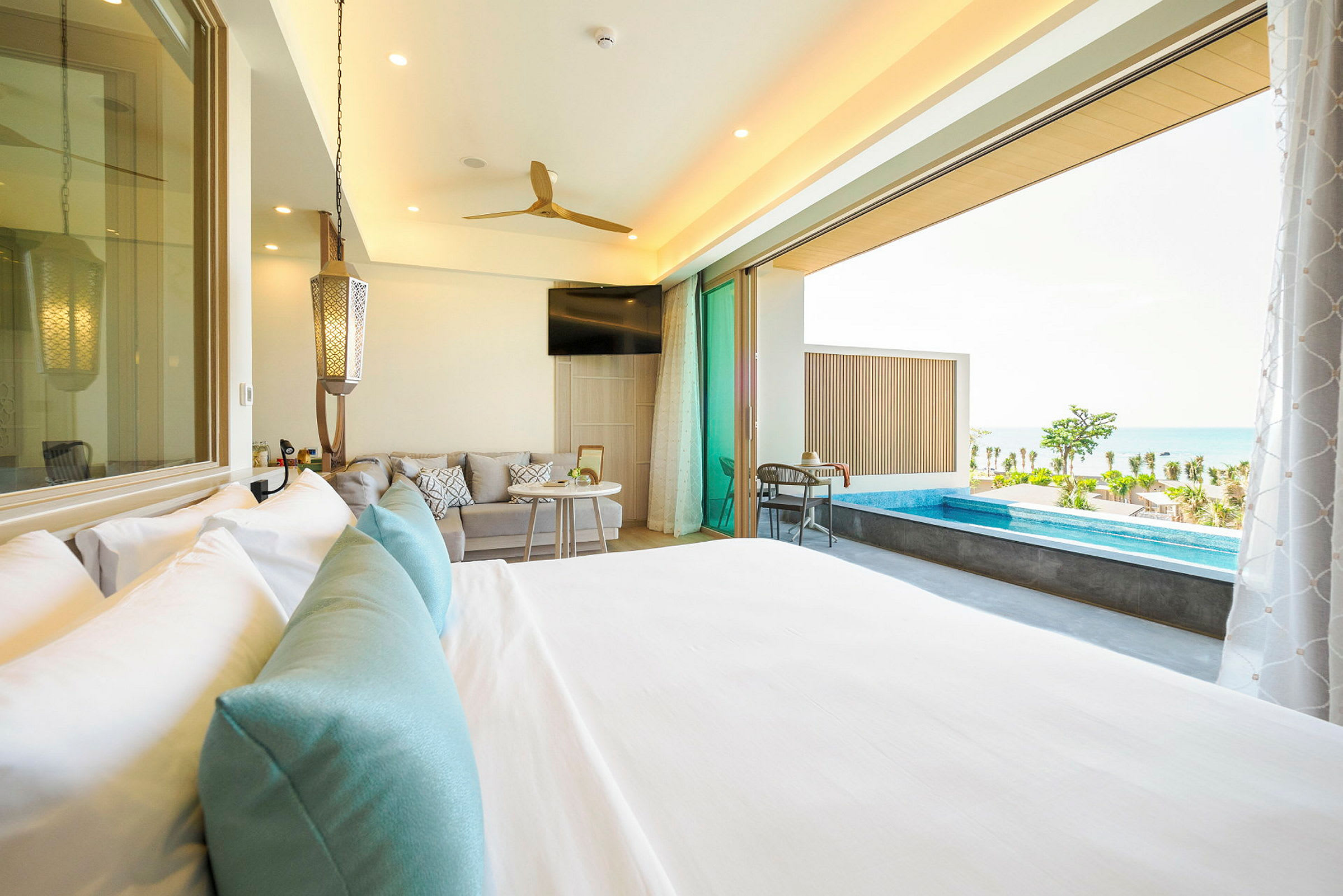 Hotellrom med seng, sittegruppe og utgang til terrasse med lite basseng og havutsikt. (AI-generert tekst)