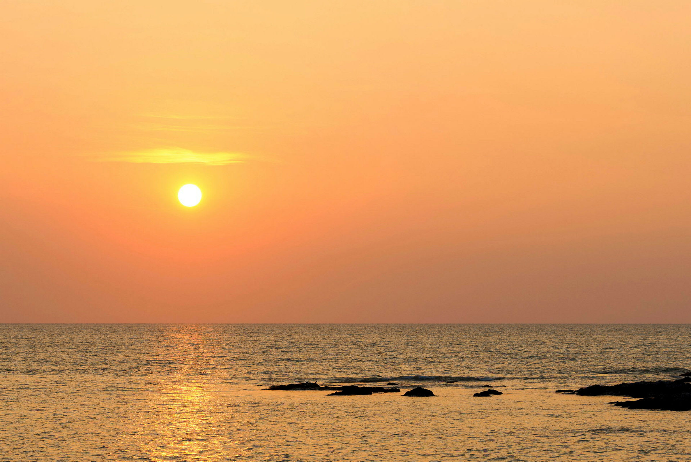 Solnedgang over havet med steiner i vannet. (AI-generert tekst)