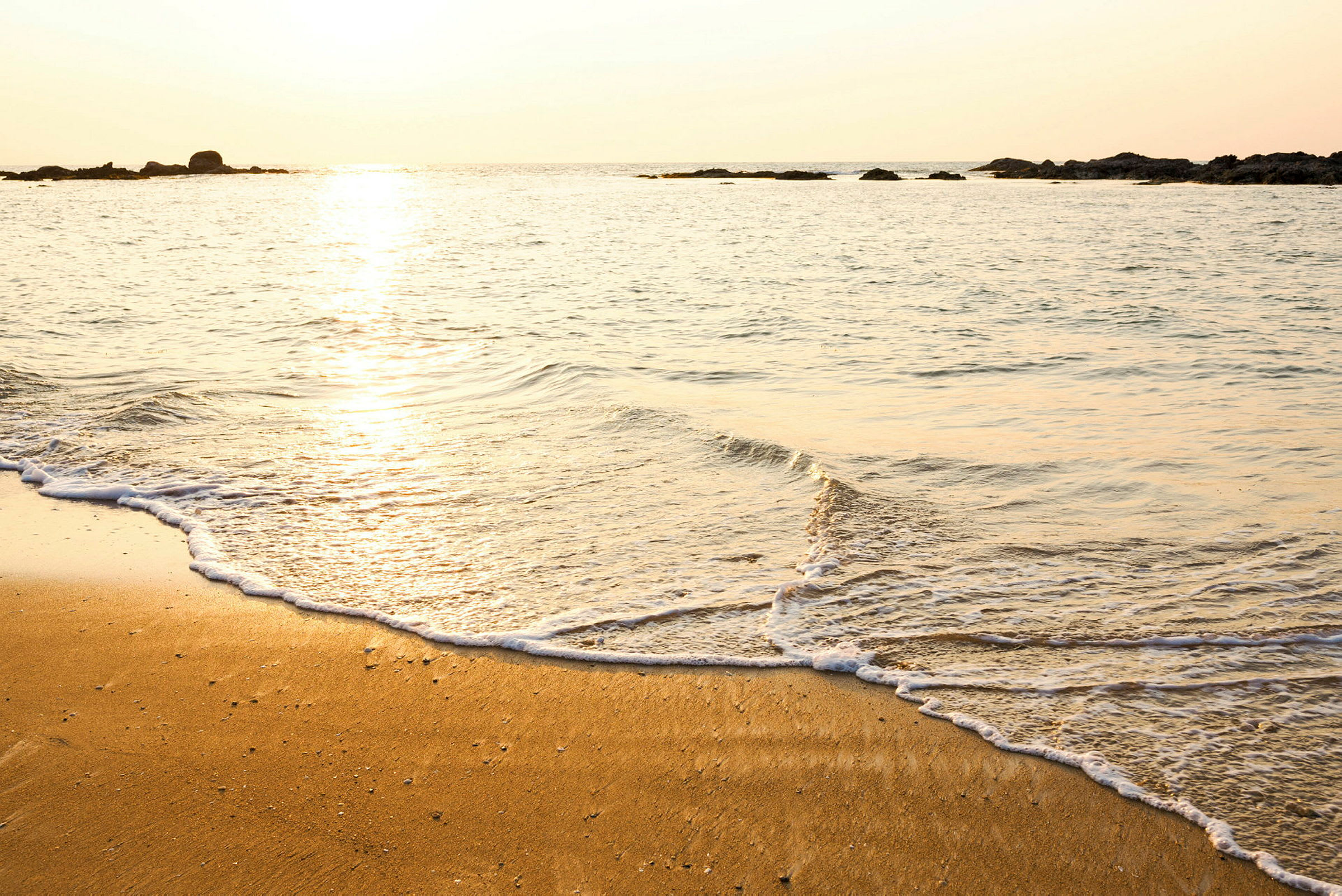 En strand ved havet med solnedgang. (AI-generert tekst)