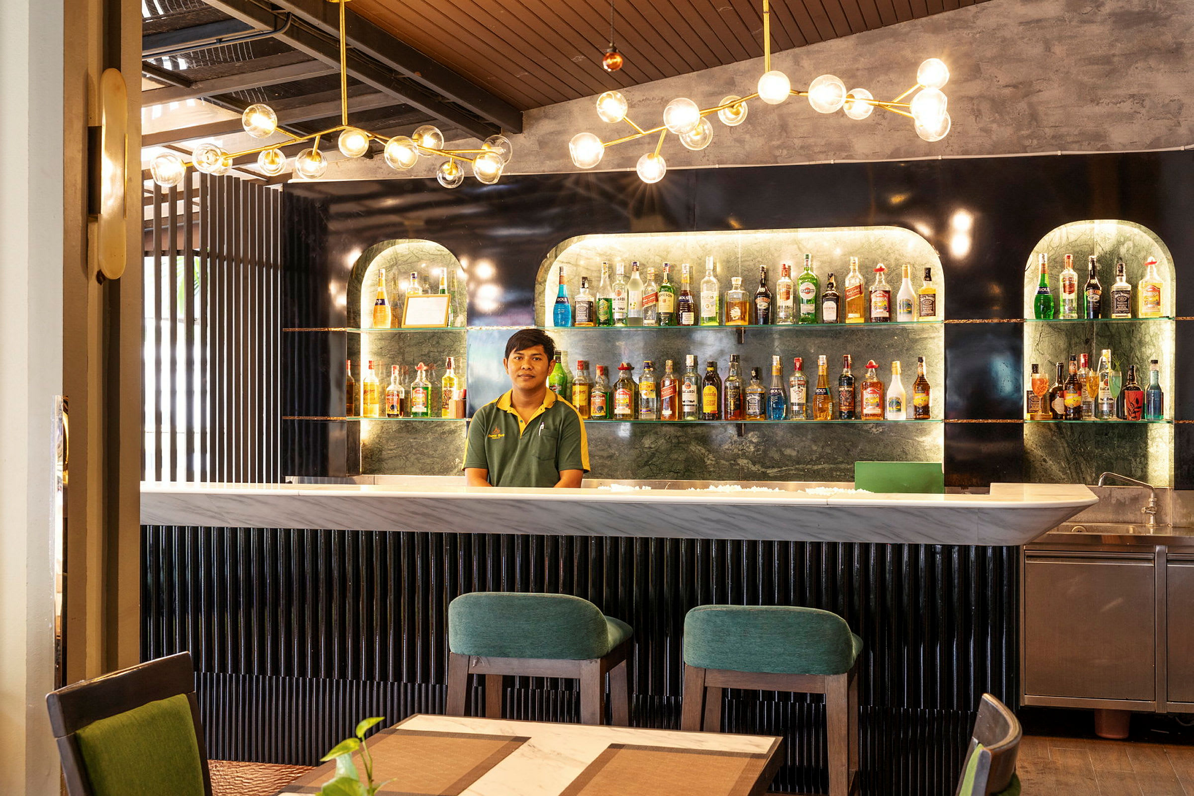 En moderne bar med flasker plassert på hyller og moderne møbler. (AI-generert tekst)
