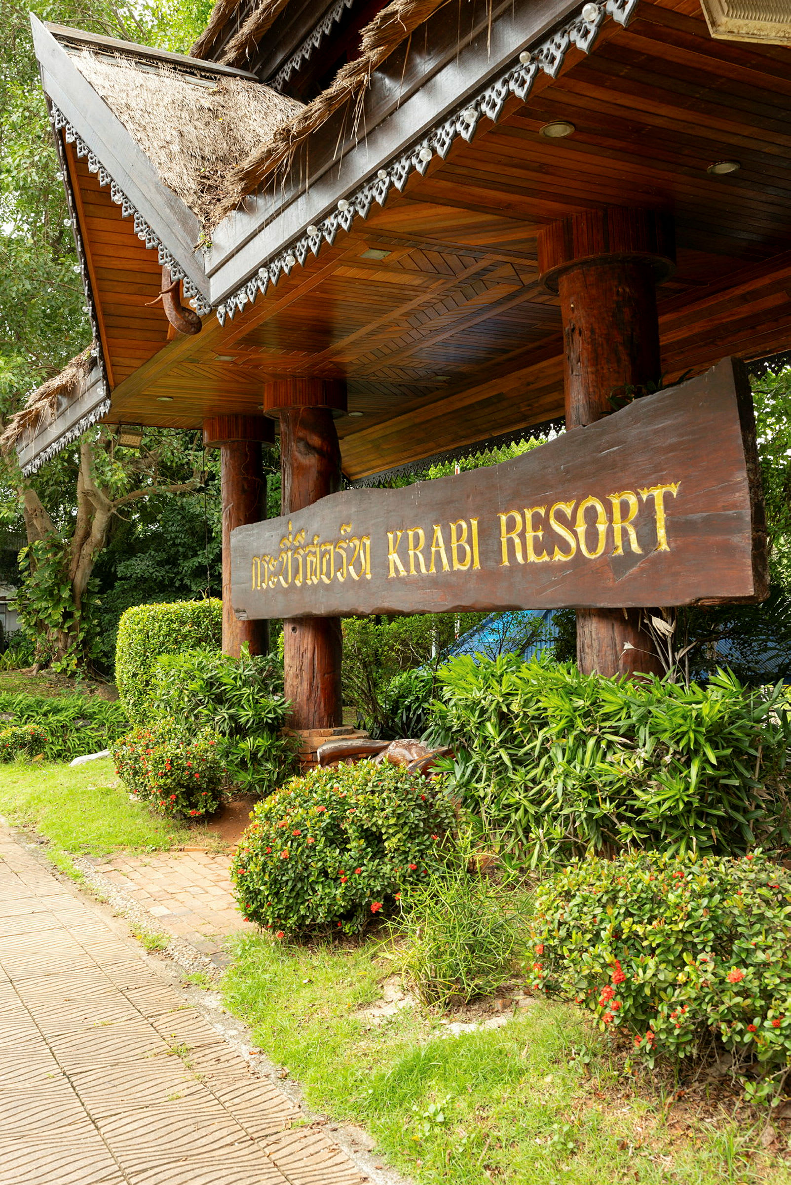 Skiltet ved inngangen til Krabi Resort, omgitt av grøntområder. (AI-generert tekst)